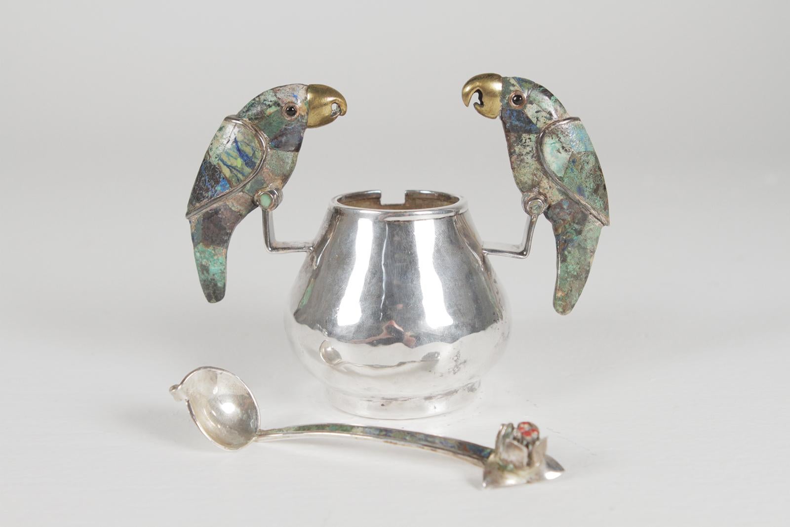 A stunning set of silver plate sugar and creamer by Los Castillo Mexico. The hand-hammered pieces with remarkable inlay stone parrot handles. Blue and green color on the handles, marked on base. The sugar with a flower top spoon inlaid with