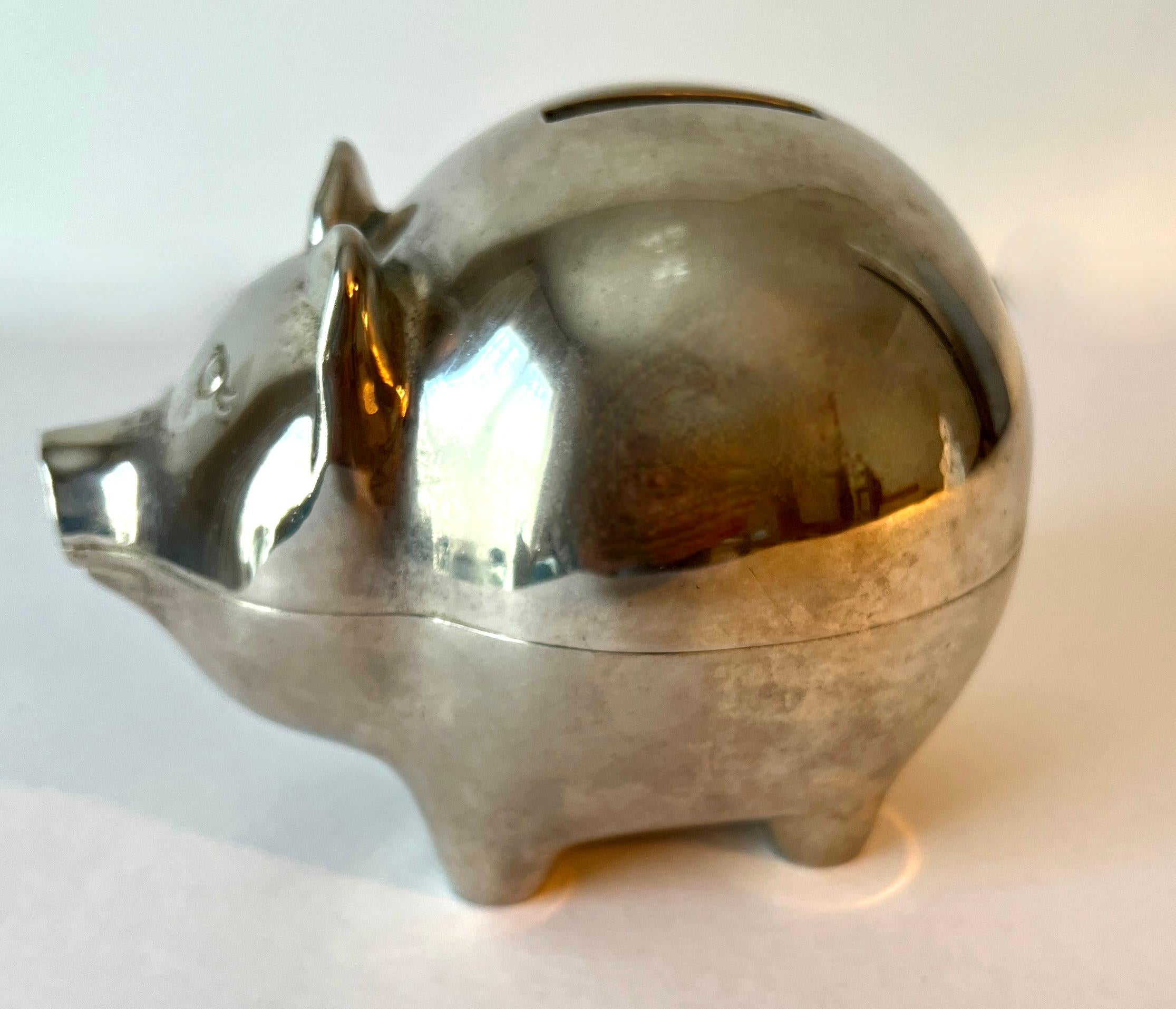 Ein entzückendes und sehr hübsches, ikonisches Sparschwein - die perfekte Ergänzung für jedes Kinderzimmer, als Babygeschenk oder sogar auf einem Schreibtisch oder Arbeitsplatz.  Die Bank sieht aus wie Silberblech und Chrom, trotzdem ist sie