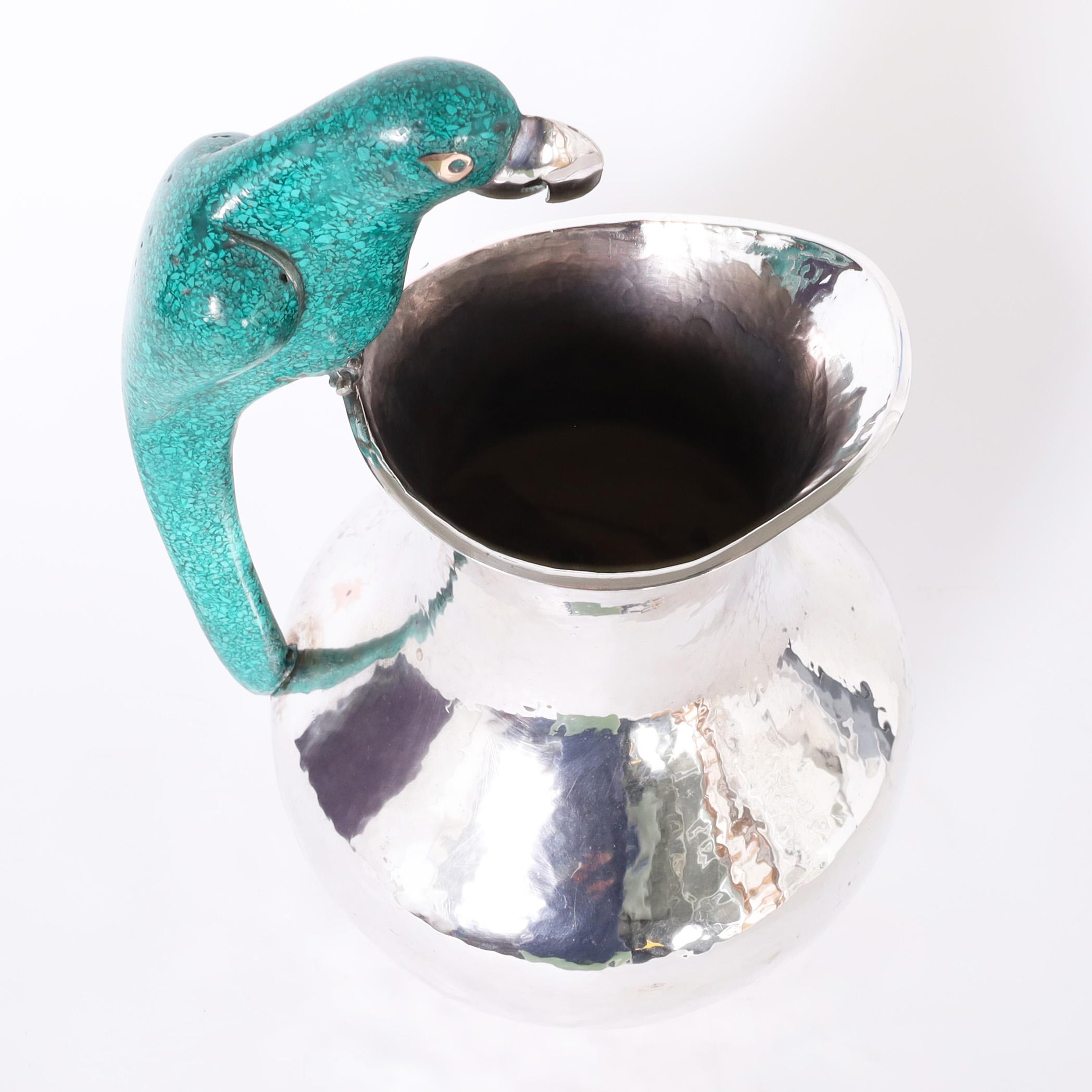 Standout vintage pitcher, in the style of Los Castillo, handcrafted in silver plate over hammered copper, featuring a terrazza clad parrot as a handle. 