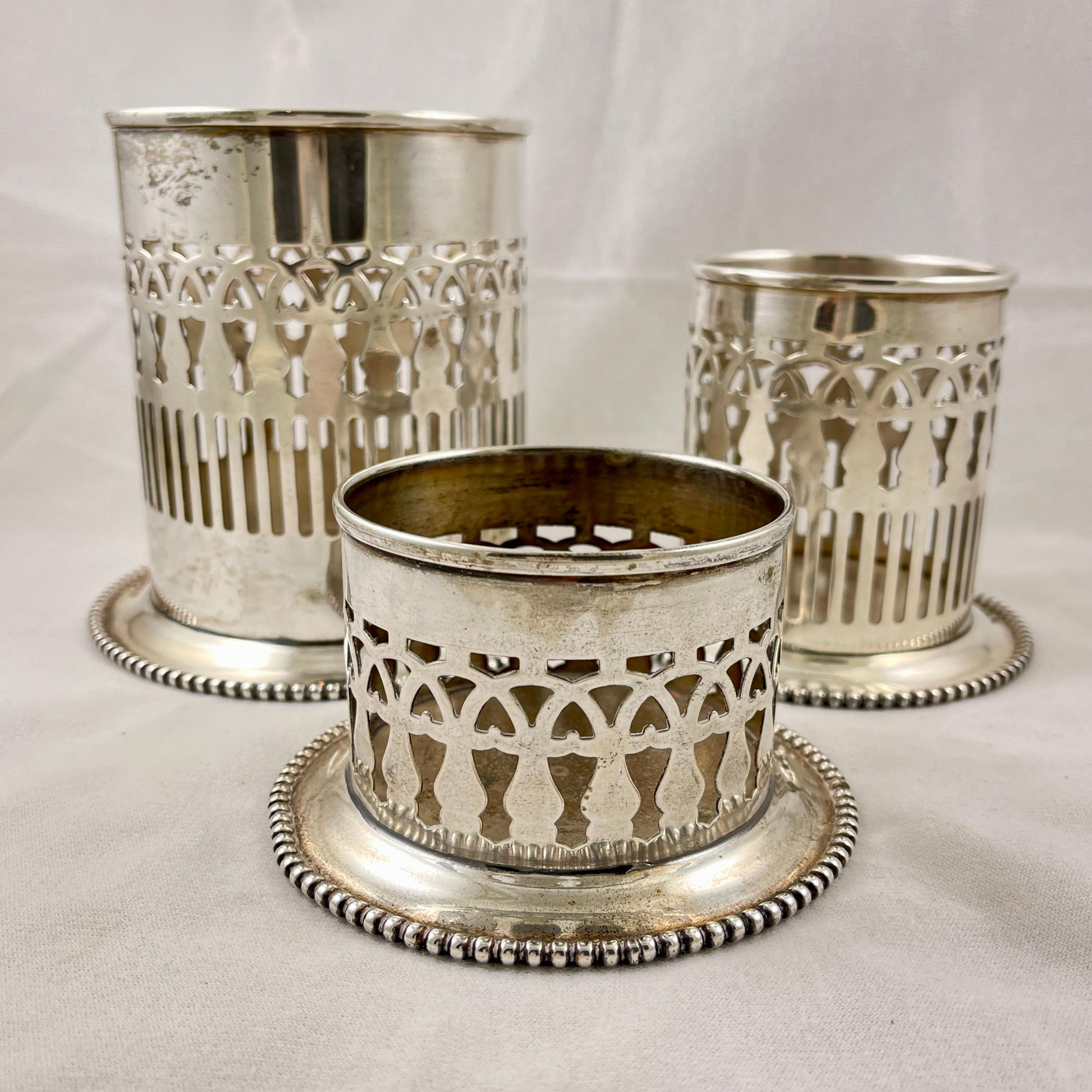 
A set of three silver-plated bottle holders or coasters, circa 1920-1930.

The set is graduated in size for holding either wine or condiment bottles, such as English mustard, steak sauce, or a hot sauce.

The bodies of the holders are in a Gothic