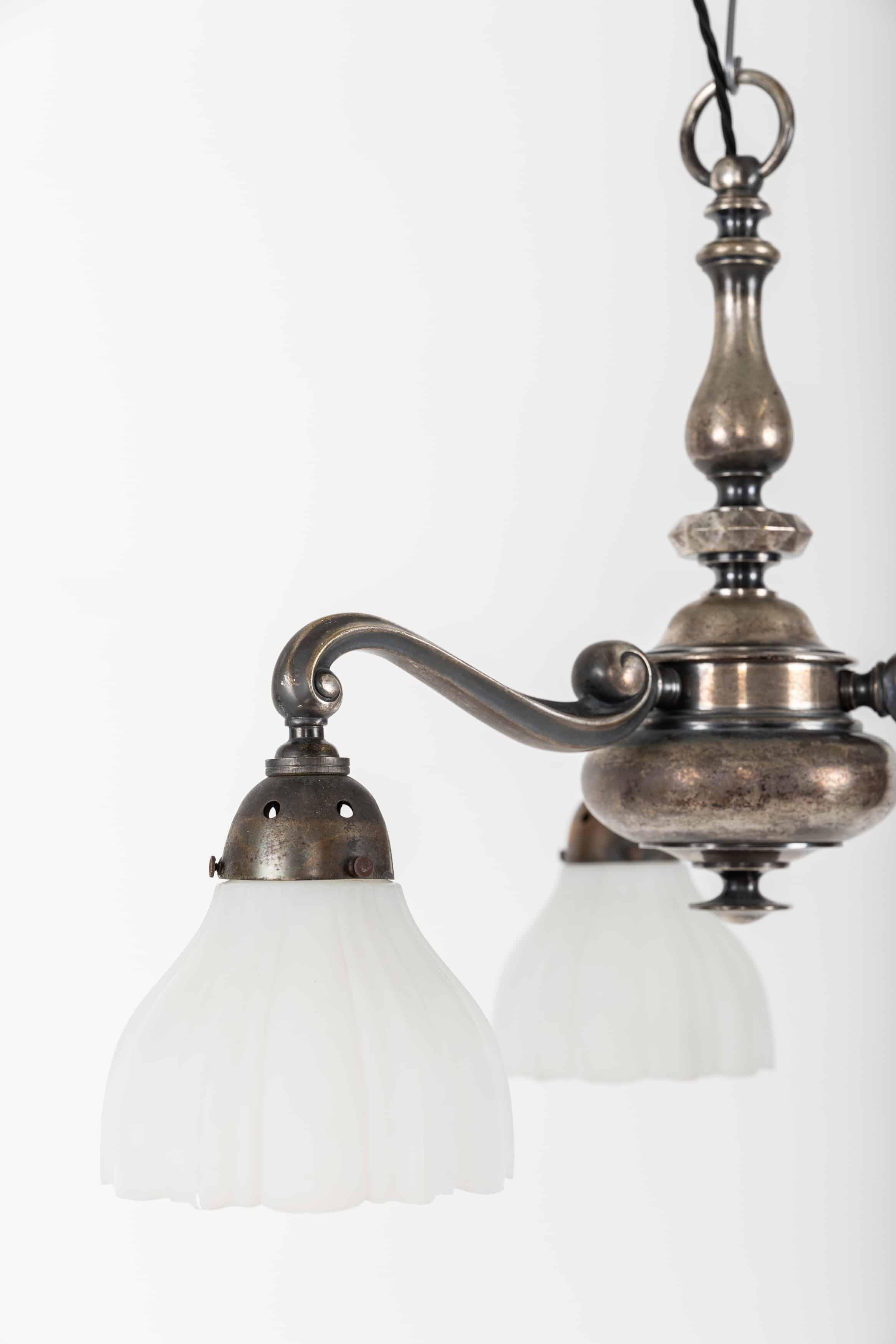 An elegantly formed three-arm ceiling pendant with opaline glass shades. c.1920

Made entirely of silver plated brass which has aged and tarnished over the past century to leave a stunning patina. Three pressed matte opaline perimeter shades