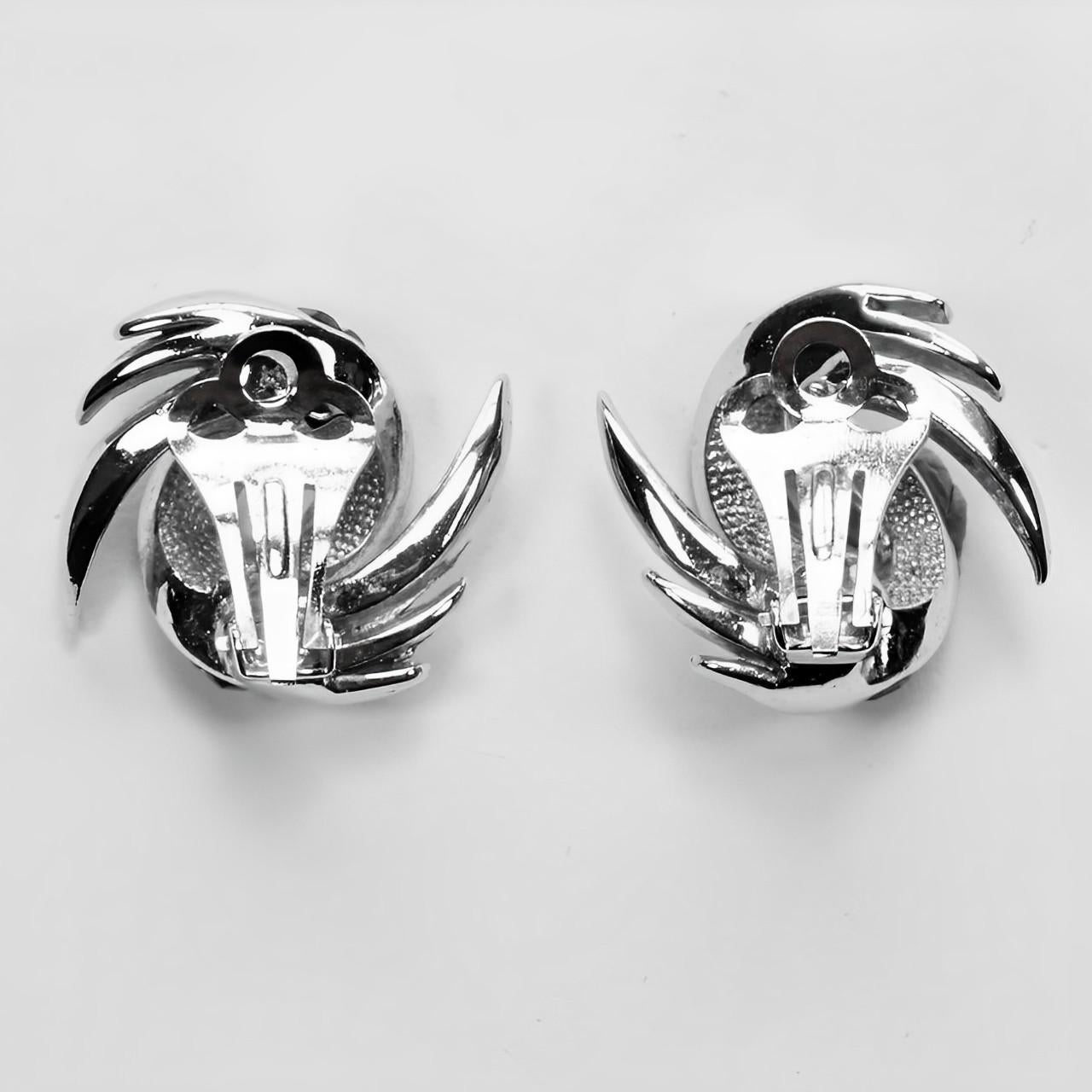 Beautiful silver plated abstract feather design clip on earrings, featuring red baguette and round clear rhinestones. Measuring length 2.8 / 1.1 inches by width 2.6 cm / 1 inch. They are in very good condition.

These stylish vintage earrings are