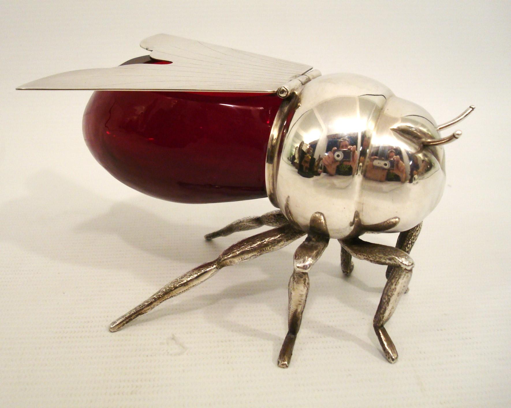 Abeja melera de plata y cristal rojo. Inglaterra, principios del siglo XX.
Marcado Elkington Plate y fabricado por la tienda que lo vendió en Montevideo (Uruguay) Broqua & Scholberg Montevideo.

Estamos especializados en la venta de Art Decó y Art