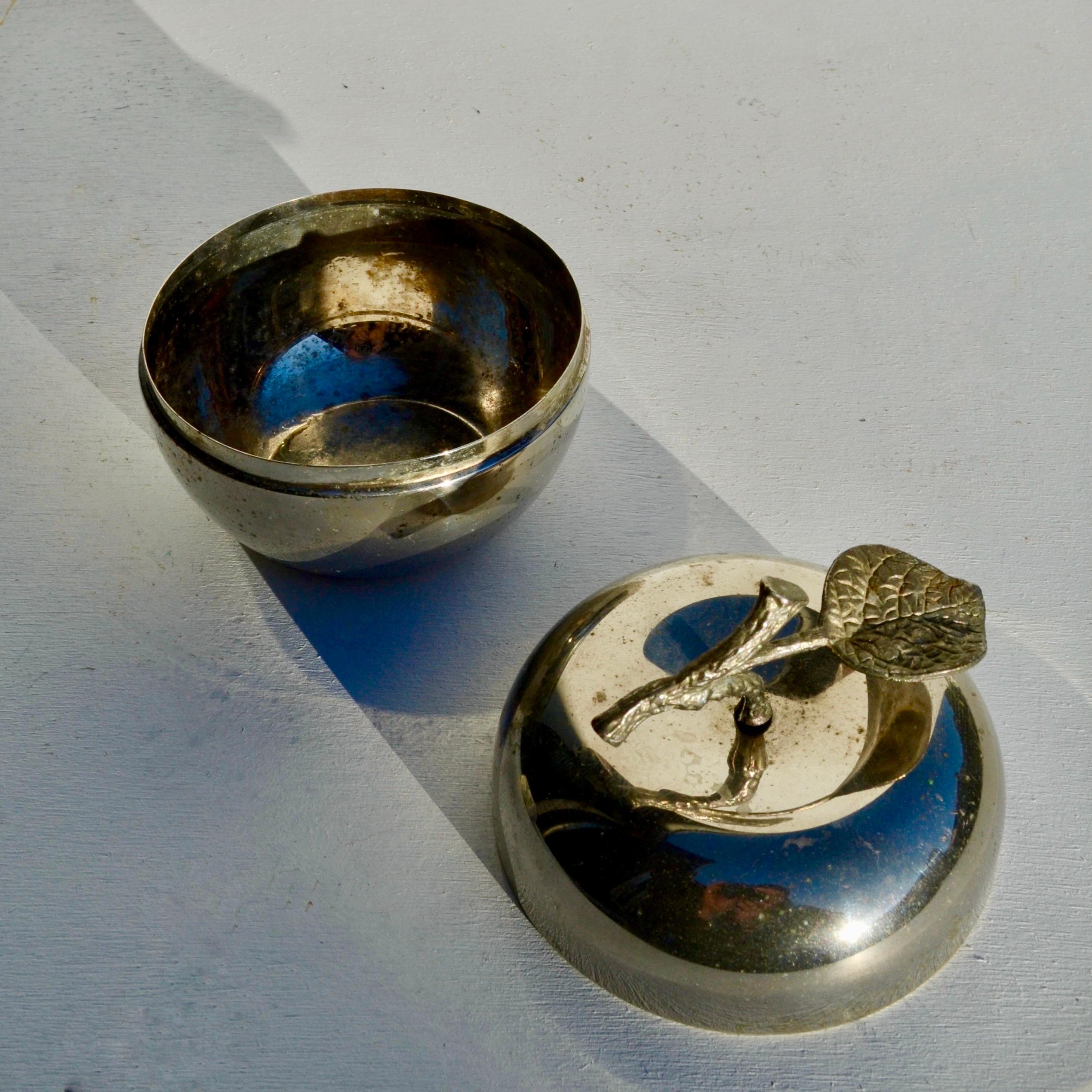 Graziosa scatola decorativa a forma di mela, realizzata in metallo argentato, Francia, circa 1970.
Il design scultoreo presenta una forma liscia e arrotondata con un manico di rami e foglie finemente dettagliato. La superficie presenta una superba