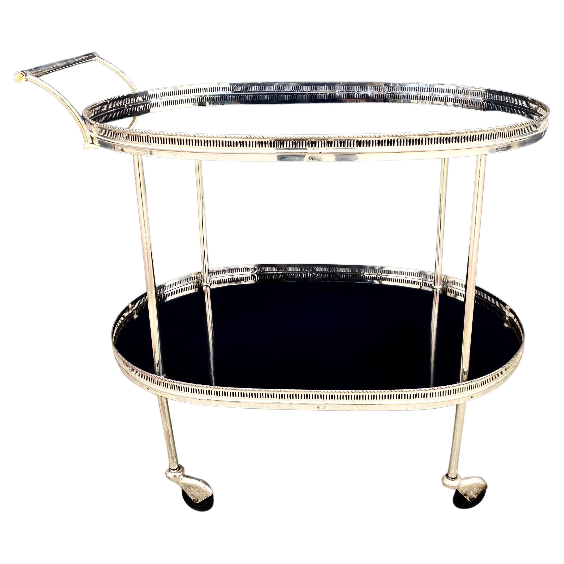 This is a superb example of a French mid-century bar cart or trolley. The cart is beautifully designed with two lacquered mahogany and silvered gallery-rimmed trays; silvered wheel covers and an elegant moderne style handle. The cart is in overall