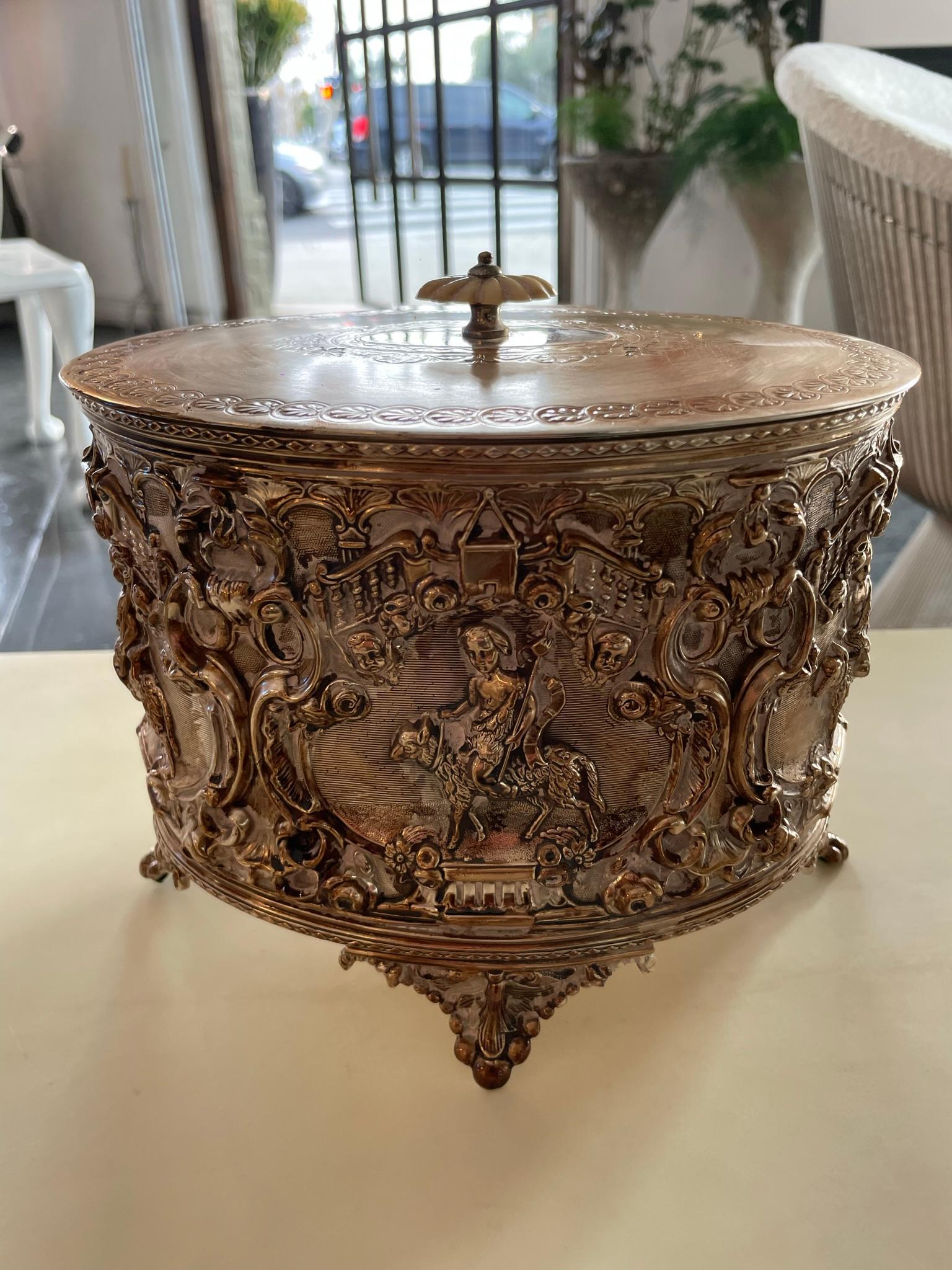 Silver-plated Biscuit Box 
oval, the hinged lid with bone finial, the body relief-cast with cherubs riding animals within scroll borders, on four feet; marked to underside 