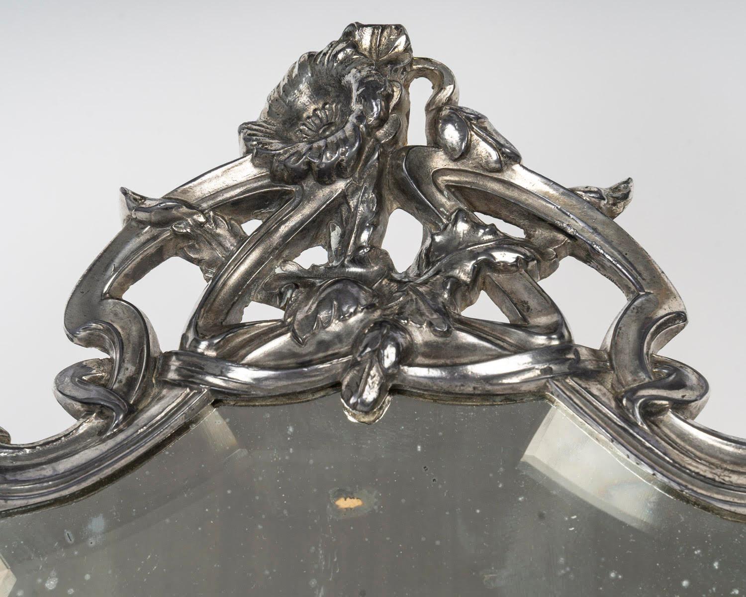 Silver plated bronze table mirror, early 20th century, Art Nouveau period.

An early 20th century Art Nouveau silver plated bronze table mirror, bevelled mirror.
H: 36cm, W: 26cm, D: 2.5cm
