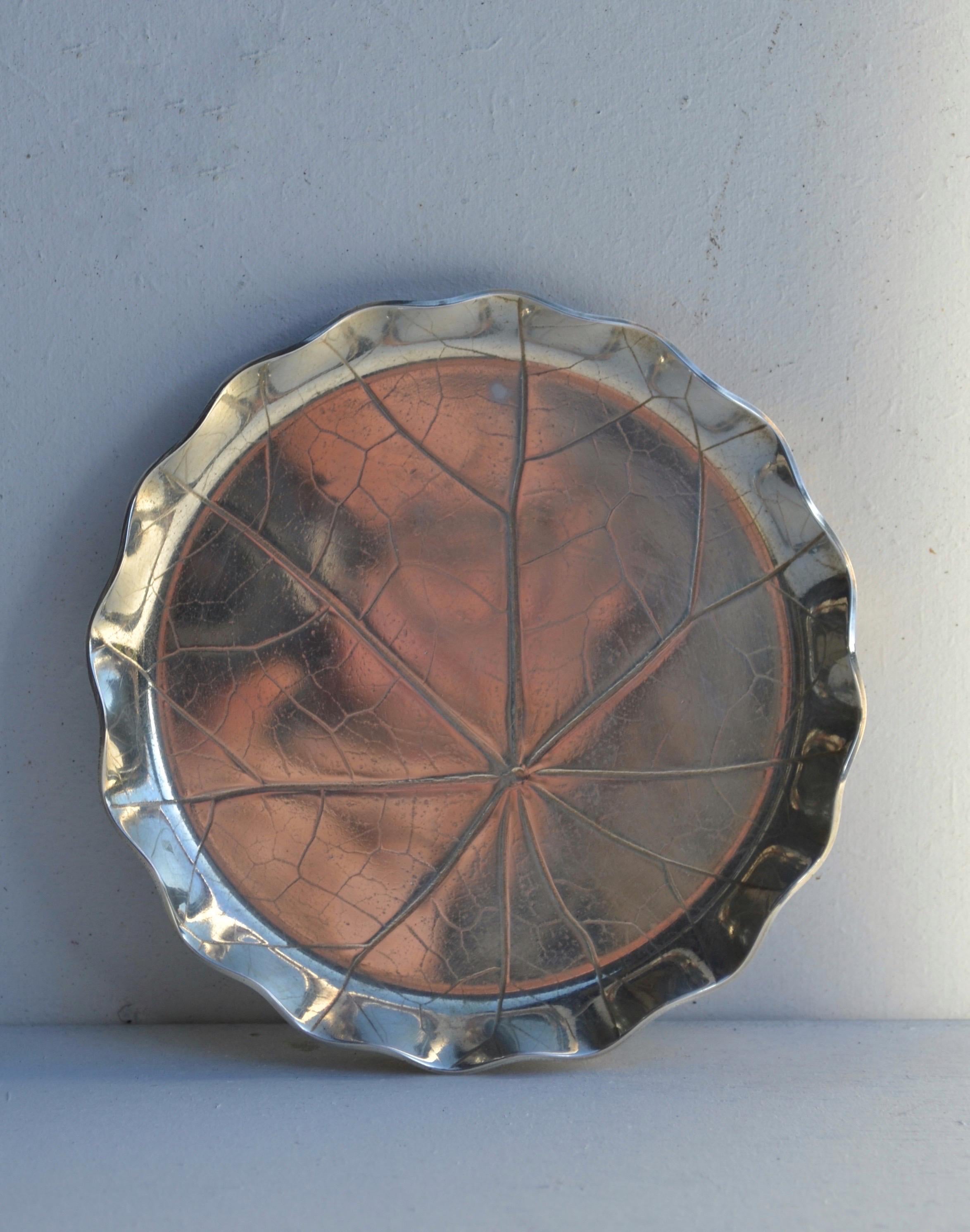 Elegante versilberte Auffangschale von Christofle aus den 1970er Jahren.
Das Stück hat eine organische, von Blättern inspirierte Form mit fein gravierten Adern und einem sanft gewellten Rand. Sein raffiniertes, zeitloses Design macht ihn zu einem