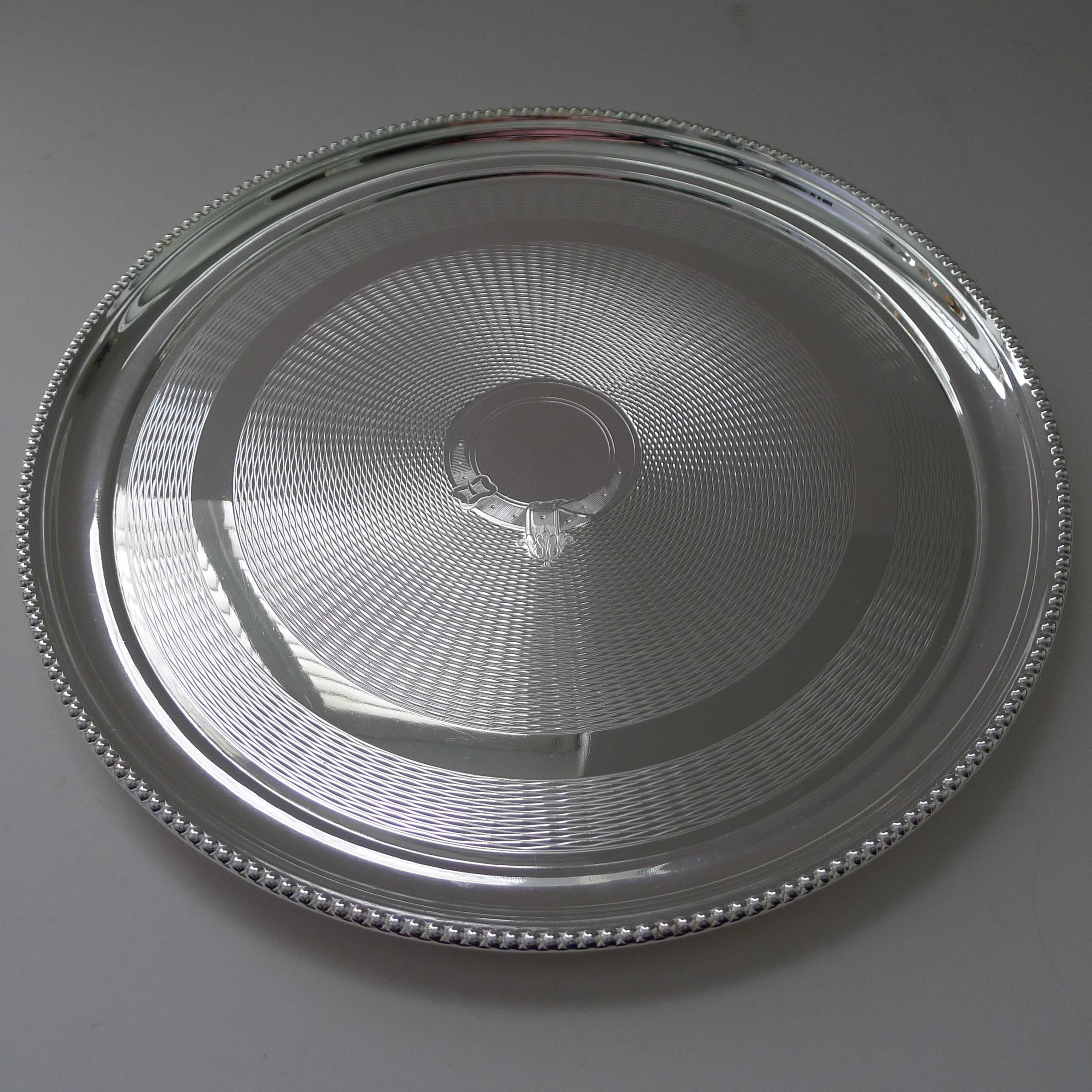 A good sized circular cocktail or drinks tray by the top notch English silversmith, Walker & Hall dating to c.1900.

A stunning example with highly decorative engine turning and a central belt and buckle motif, the central cartouche is vacant