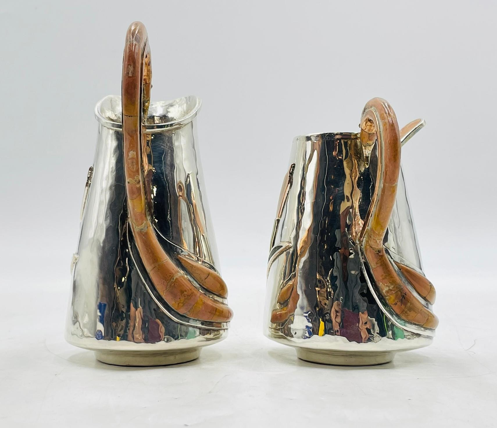 A beautifully crafted silver plated creamer and sugar set by Wolmar Silversmiths for Castillo, Mexico. Each piece is hand-hammered and adorned with sculptural cattail plant motifs in relief. The standout feature is the graceful flamingo-shaped