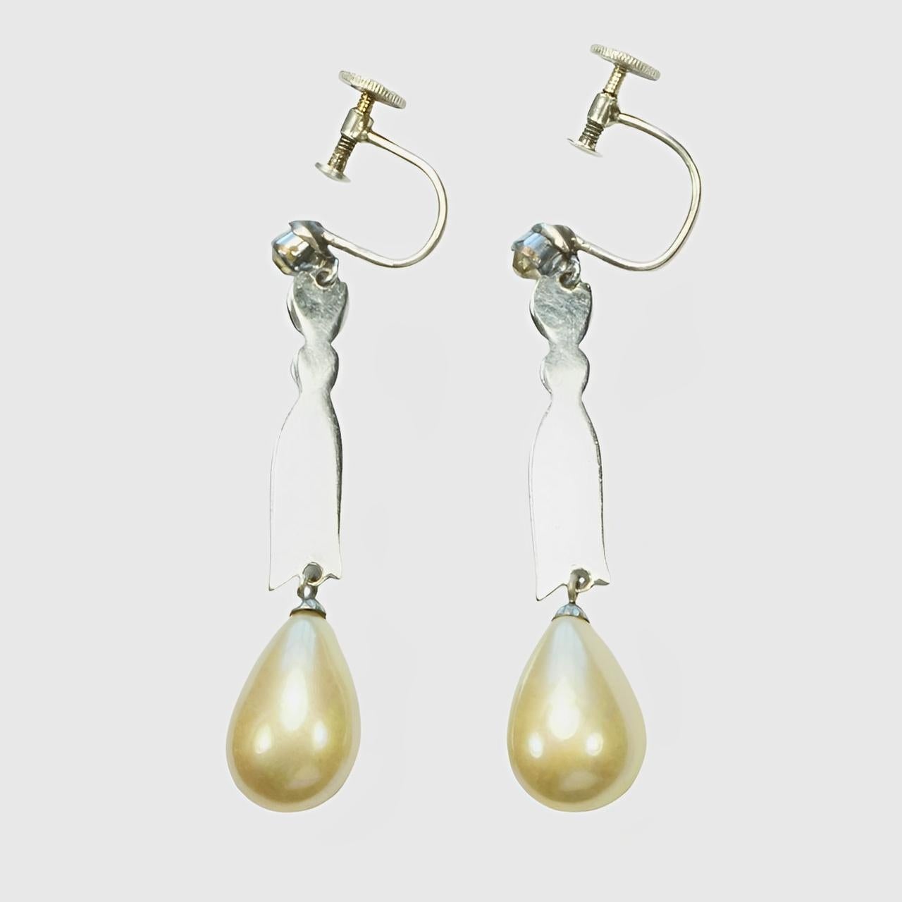 Preciosos pendientes en forma de gota bañados en plata, con perlas de imitación color crema de brillo iridiscente y brillantes. Los racores son plateados. Los brillantes son de color amarillo pálido (originalmente de este color, o envejecidos con el