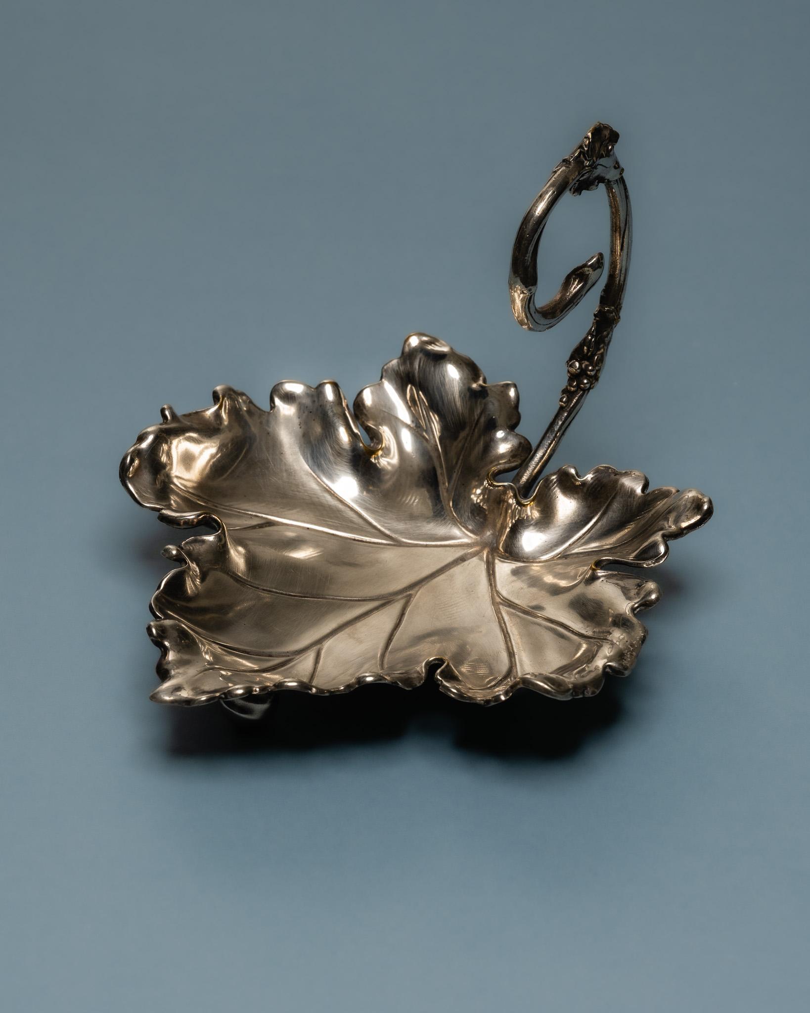 Silver-Plated Molded Metal Leaf-Shaped Trinket Dish, 1950s.
Modeled as a vine leaf with a naturalistic handle, resting on three small spherical feet. Hallmarks visible on the stem. European work from the 1950s

DV4770