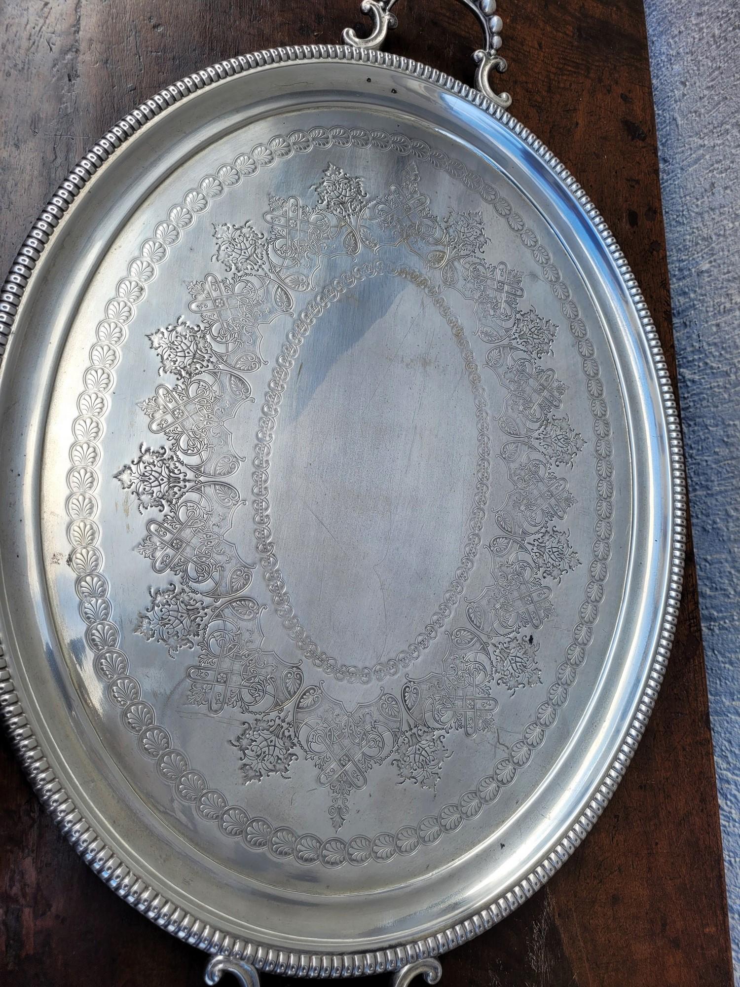 Plateau ovale en métal argenté avec poignées en forme de boule, décoré de feuilles et de guirlandes

Traces d'utilisation, rayures et légers chocs.
20e siècle.

77 x 49.5 cm