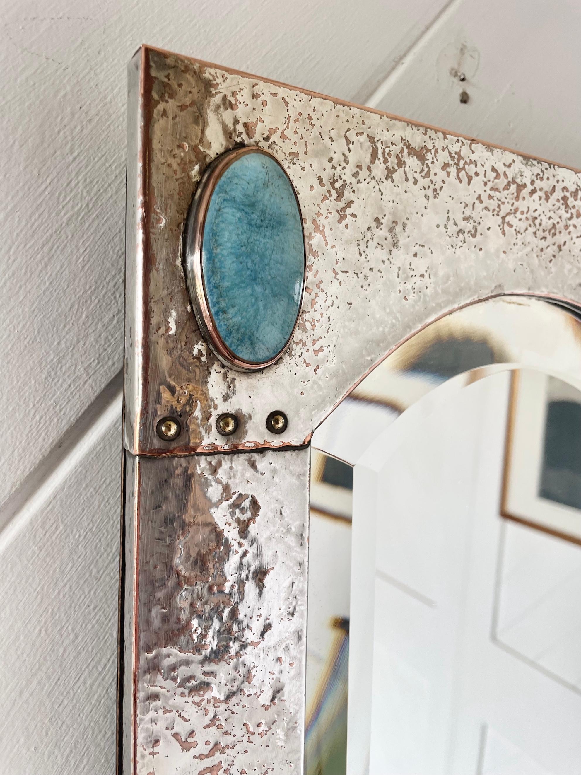 Arts & Crafts silver plate on hammered copper rectangular framed mirror

With arched bevelled glass, rivets and oval ceramic Ruskin inserts

Circa 1900 

Height 50cm.  Width 30cm.  Depth 2cm