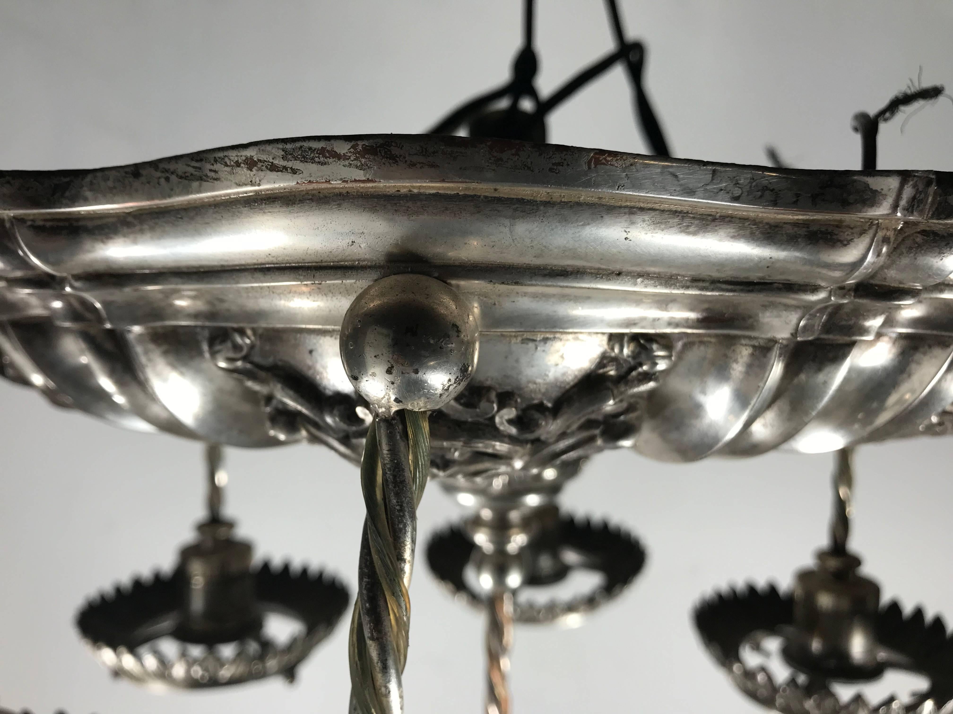 Stunning silver plated neoclassic style pendant chandelier by E.F.Caldwell, circa 1920s

Edward F. Caldwell & Co., of New York City, was one of the premier designers and manufacturers of electric light fixtures and decorative metalwork from the