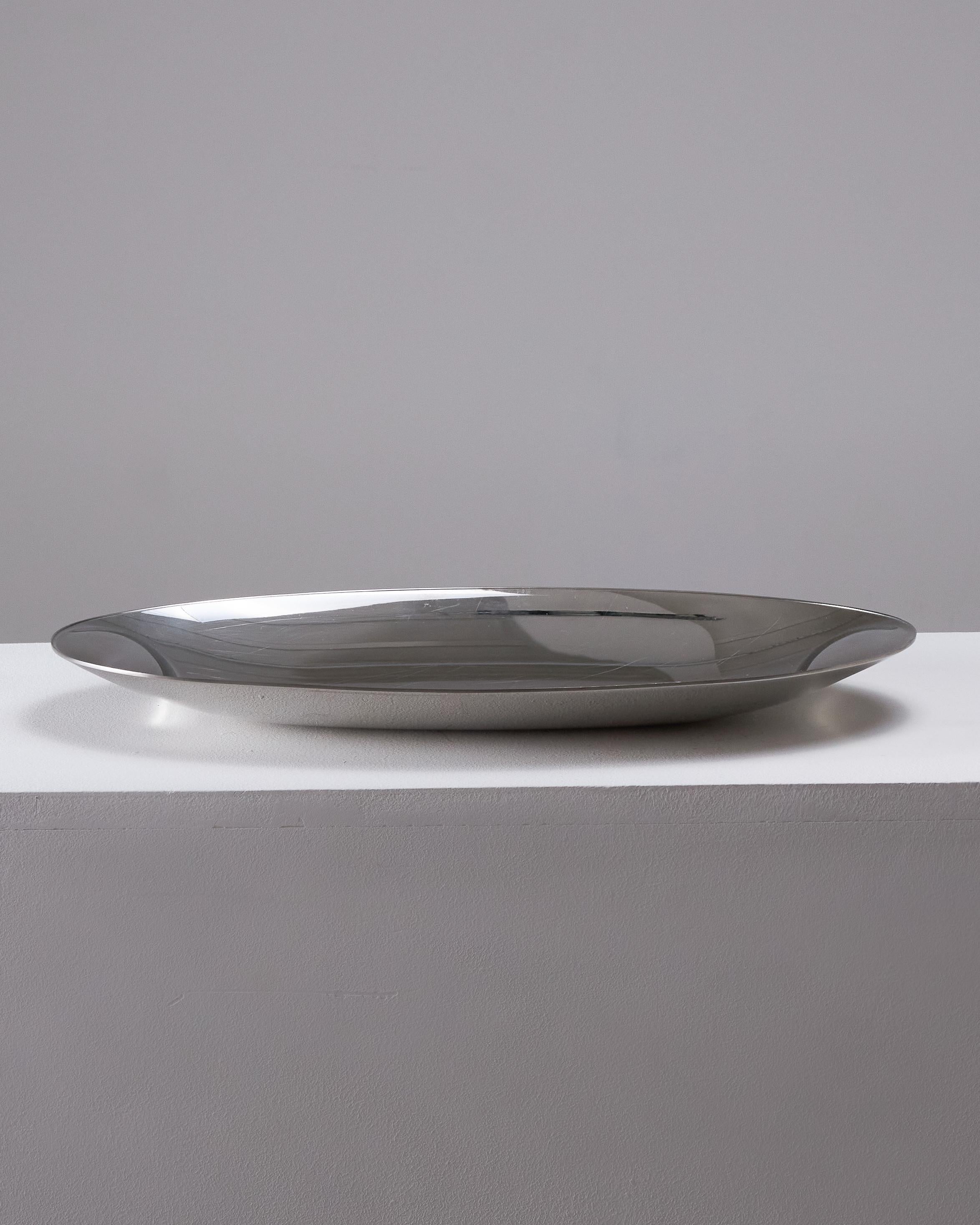 Cet élégant plateau présente une forme ovale raffinée et deux poignées latérales pour une prise en main facile. Conçue dans les années 1970 par le célèbre designer italien Lino Sabattini, elle reflète son esthétique minimaliste et sculpturale.