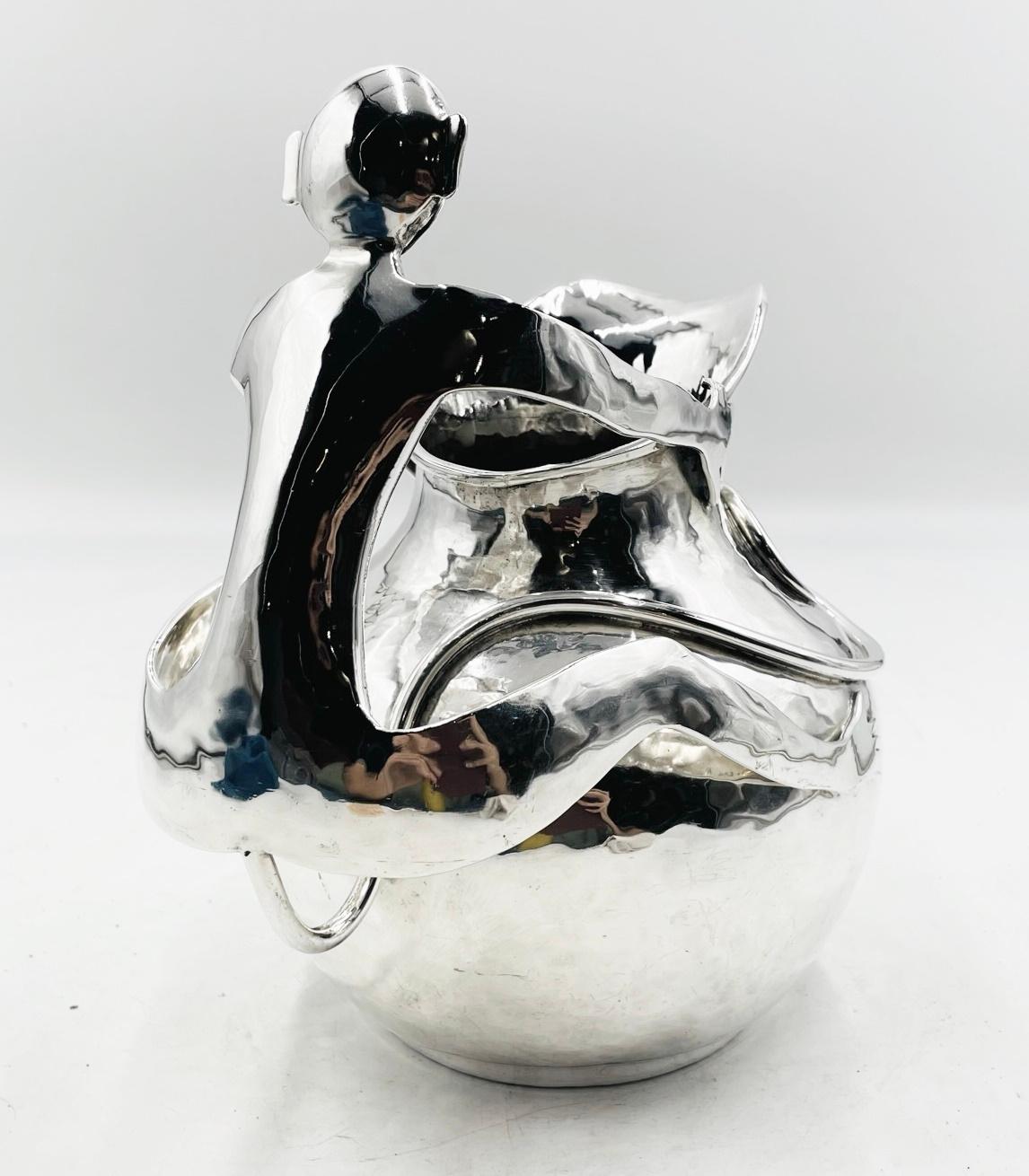 Introducing the exquisite Vintage Silver-Plated Pitcher with a Monkey Handle by Emilia Castillo, Mexico 85, Signed. This extraordinary piece of art seamlessly combines traditional craftsmanship with a playful touch, making it a true centerpiece for