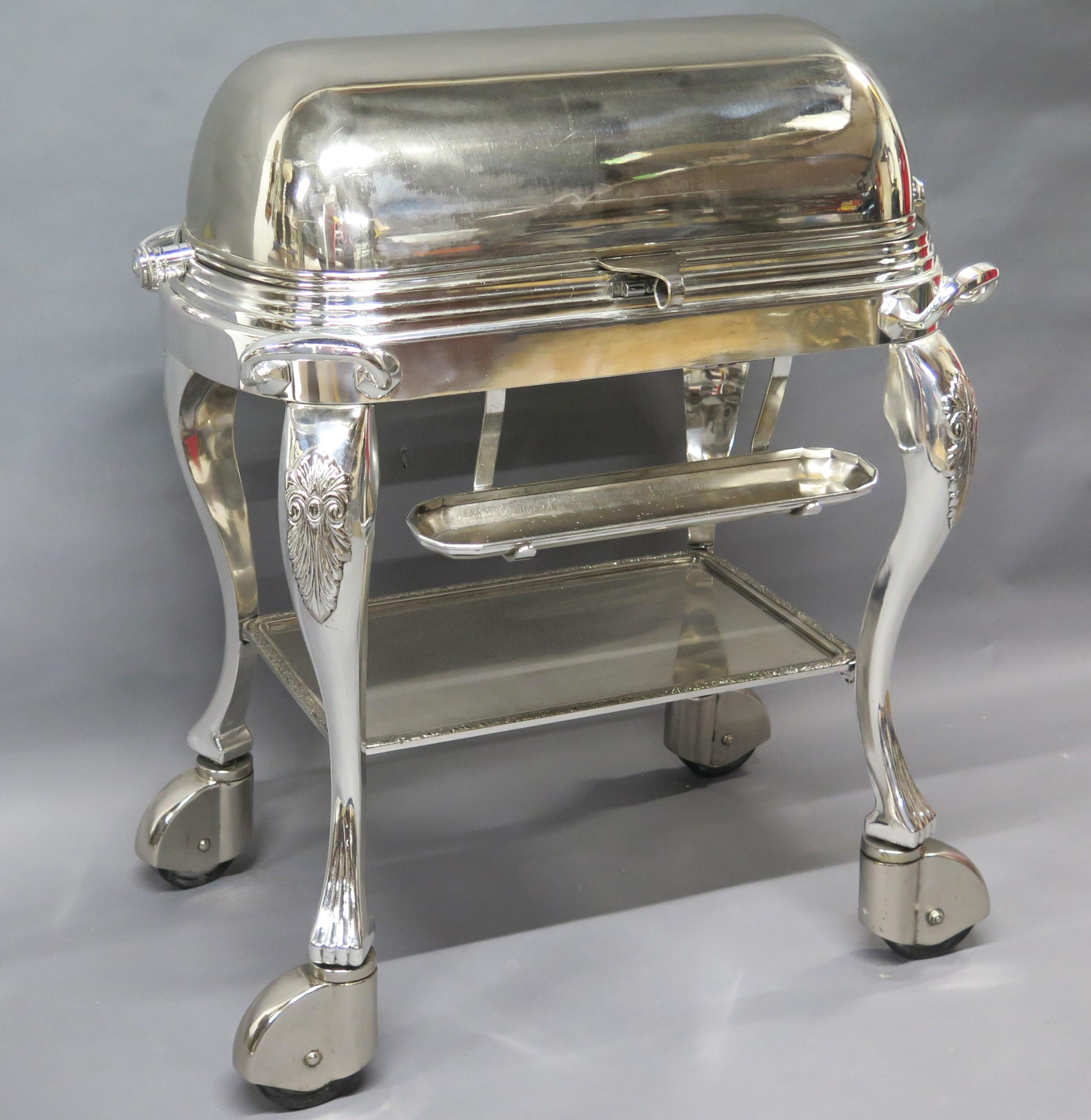 Silver plated roast beef trolley, roll top lid opens to reveal a warming tray fitted with removable cutting board and two reservoirs over three burners, coaster to one side and an oblong utensil tray front. raised on cabriole legs with large covered