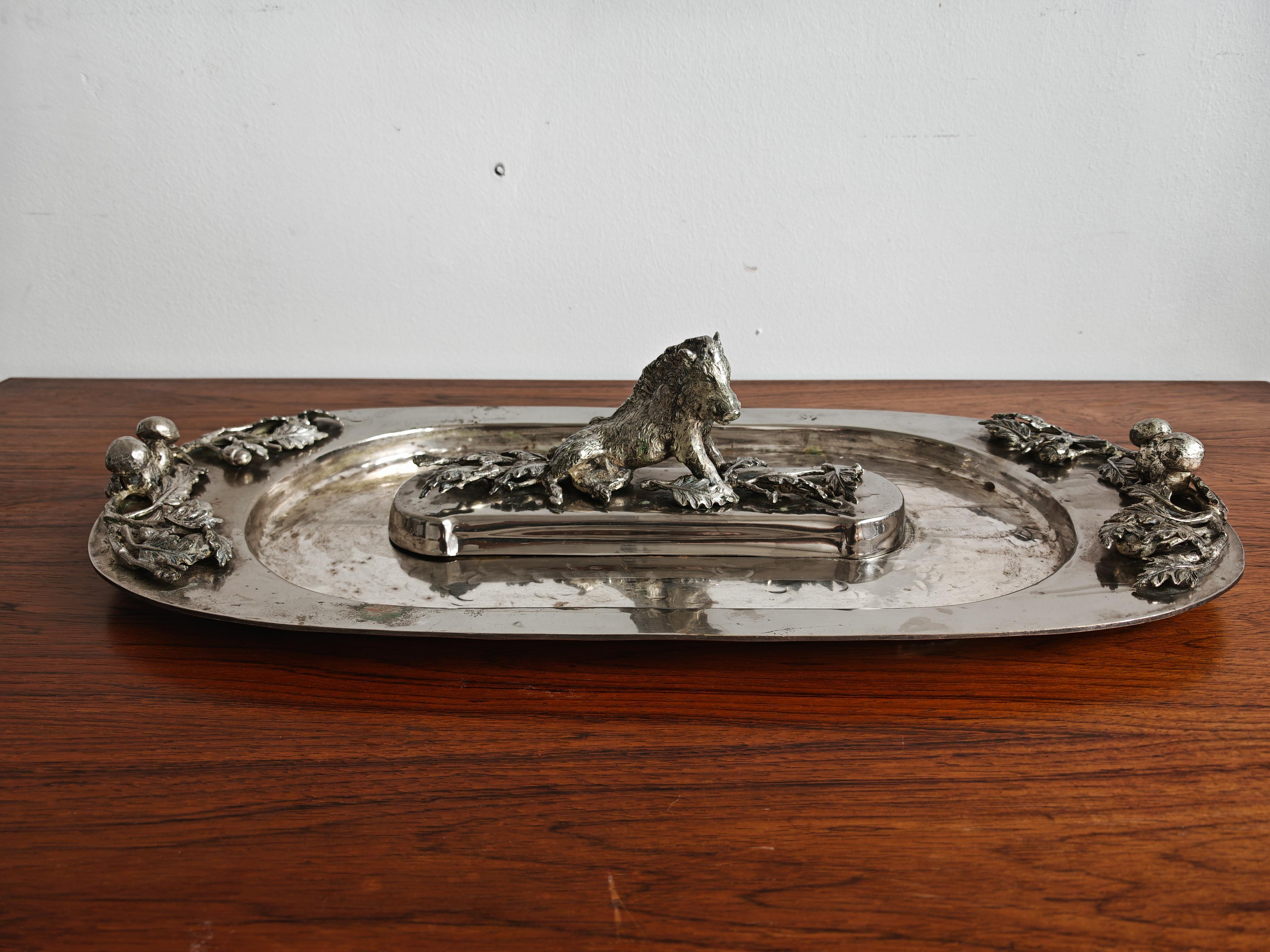 In questa inserzione troverai un sorprendente centrotavola o piatto da portata in argento Hollywood Regency disegnato da Franco Lapini. Presenta una scultura centrale di un cinghiale seduto, circondato da elementi decorativi che raffigurano fronde