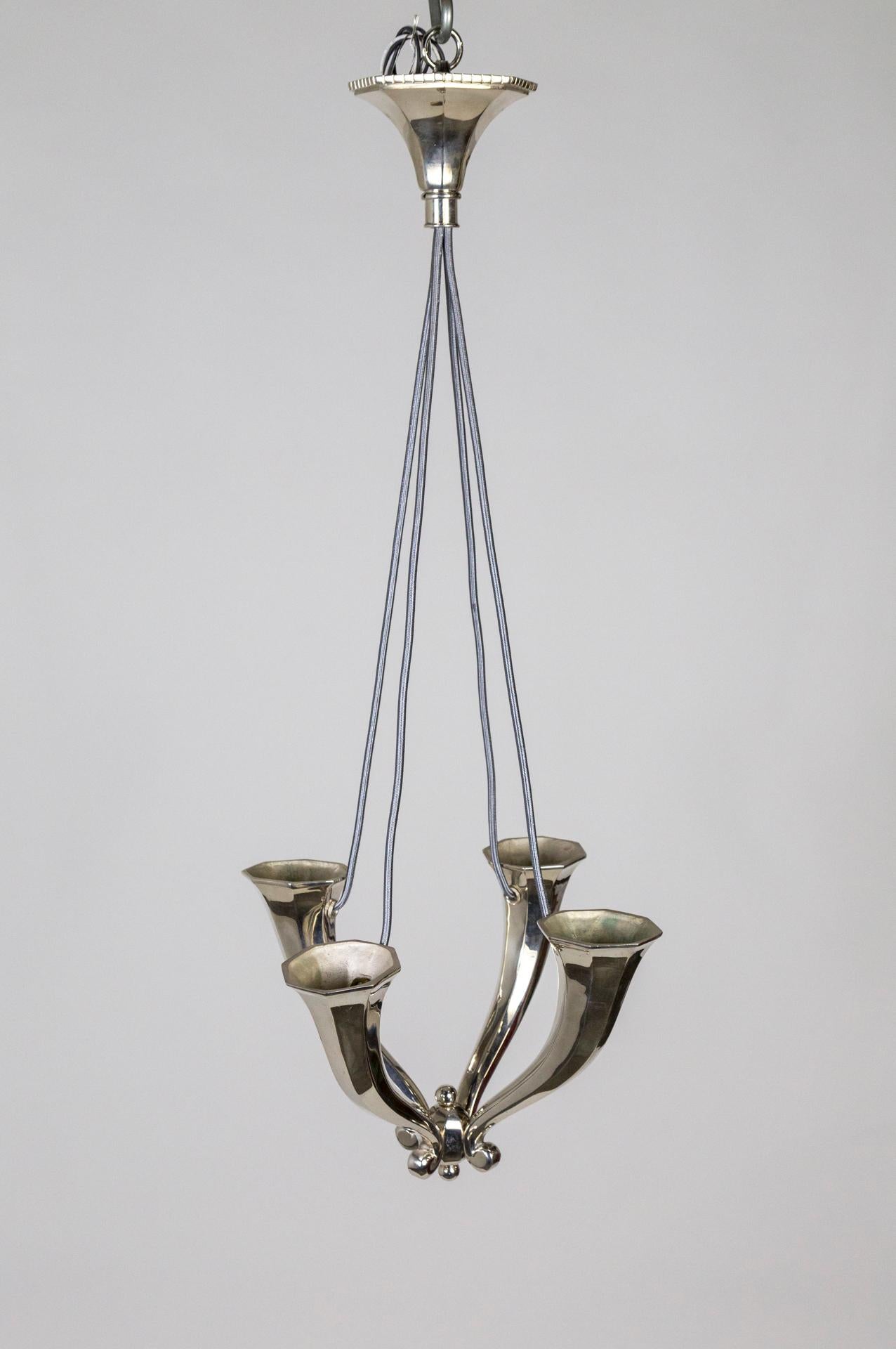 A solid, understated, shining silver chandelier with four upward facing, horn shaped arms. Recessed sockets have a clean look and light up the ceiling dramatically. Made in the early 20th century, newly silver plated and rewired with sleek,