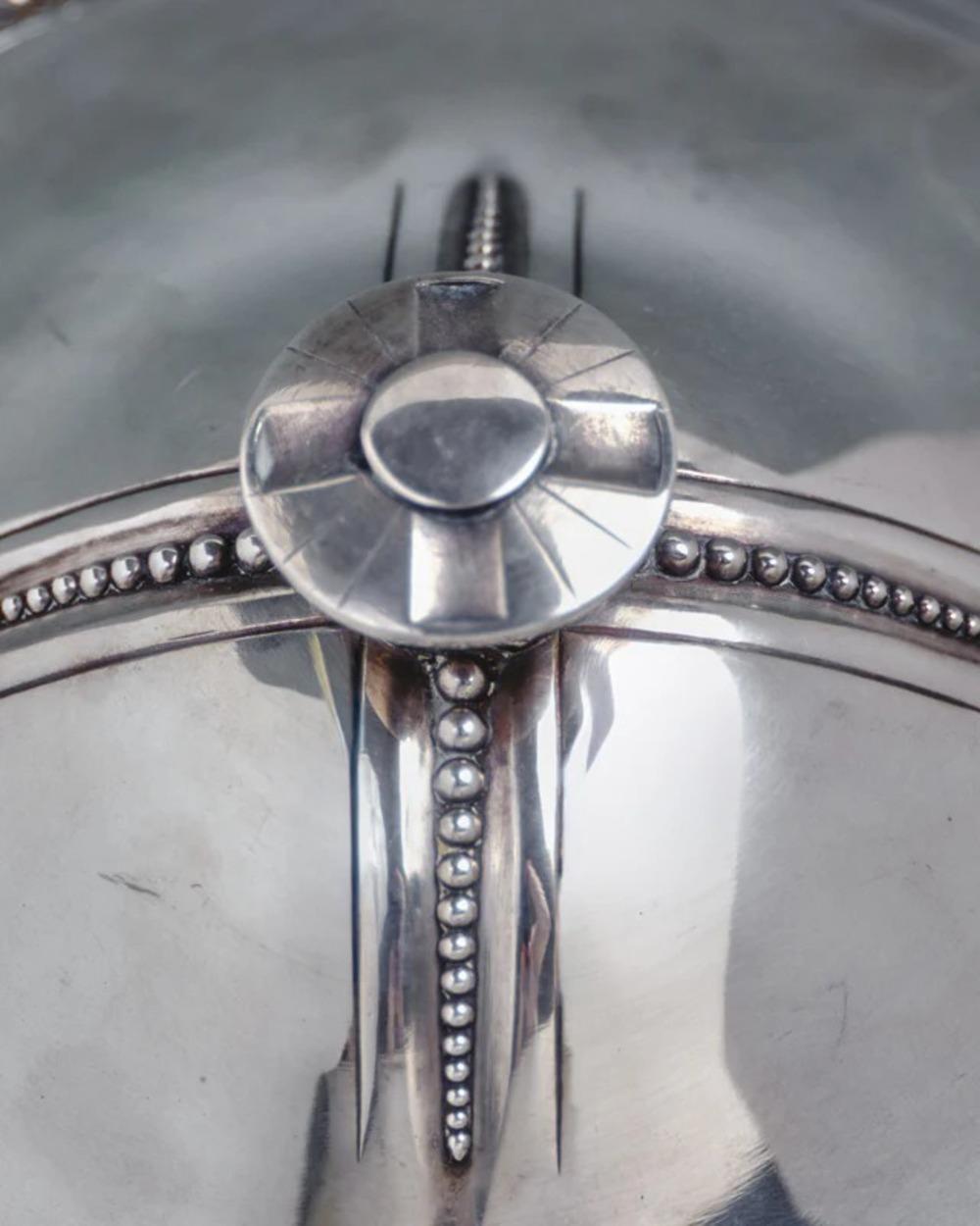 Soupière en deux parties, en métal argenté, présentant un motif perlé et géométrique de style Art déco. 