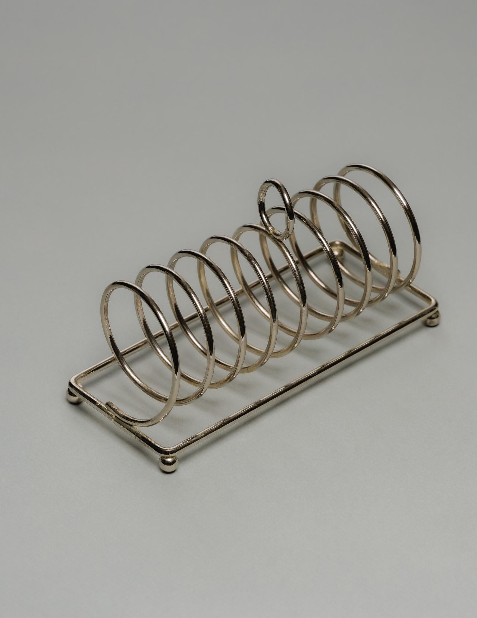 Silver-Plated Toast Rack with Six-Arched Geometric Structure and Circular Handle, 1930s.
English work, hallmarked on the base with typical British silver-plated marks. Very good condition, with light age-appropriate patina

DV4742