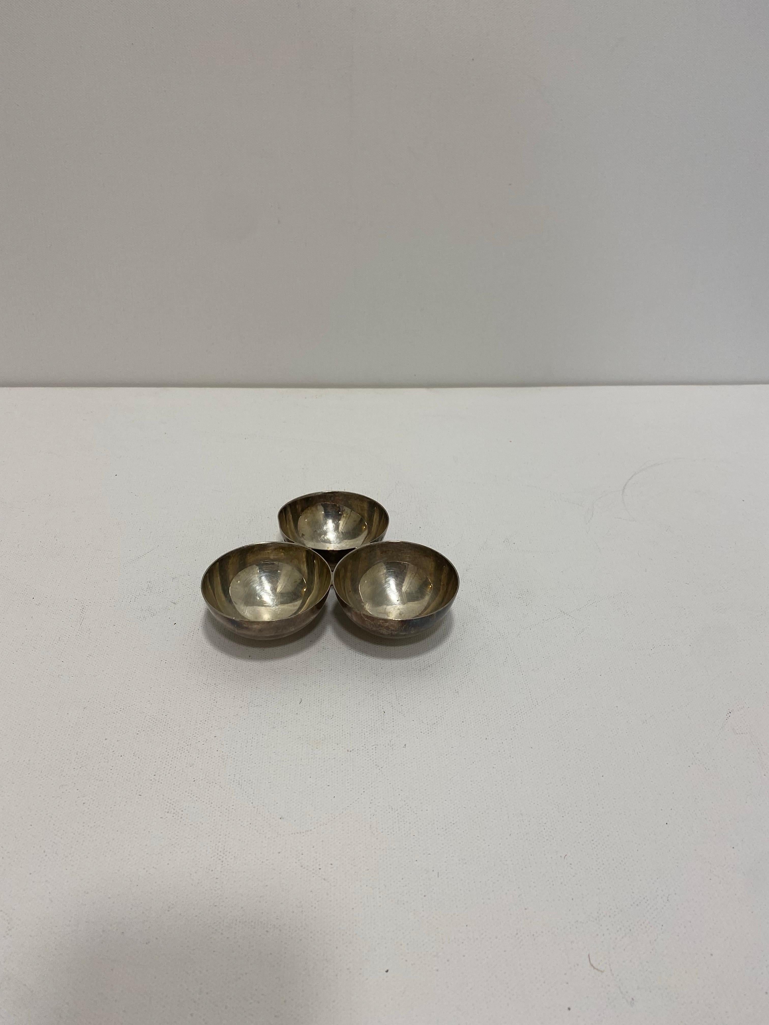 Ce set de trois bols ronds, importé d'Anvers et datant de la période Art déco des années 1940, est à la fois élégant et minimal. Il se compose de trois bols de la taille d'un coquetier qui sont reliés entre eux. 
Parfaite comme assiette à sauce,