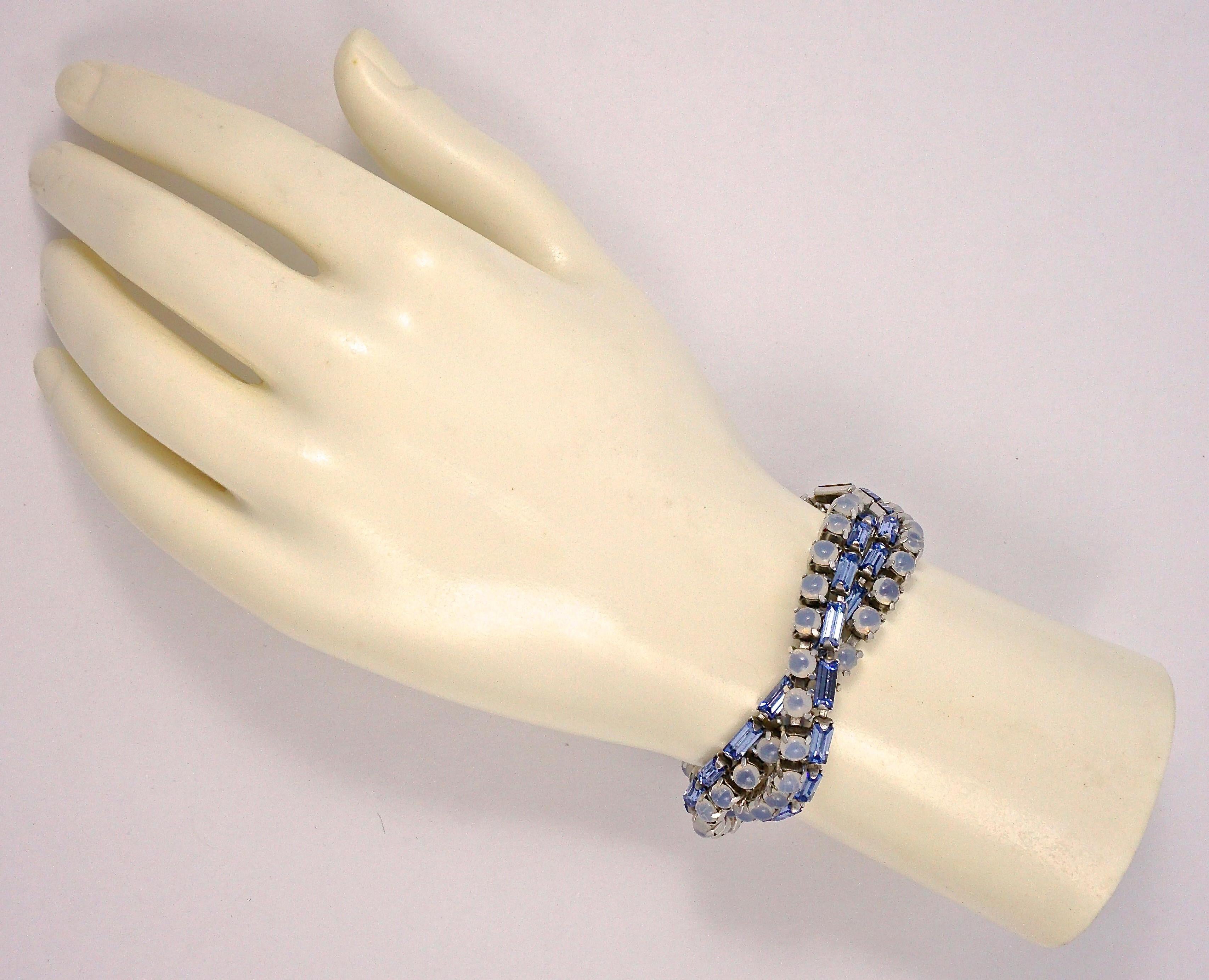 Beautiful silver plated twist bracelet with a safety chain, featuring mid blue baguette rhinestones and round blue grey moonglow cabochons. The clasp is finished with a single round blue rhinestone. Measuring length 18.8cm / 7.4 inches by width in