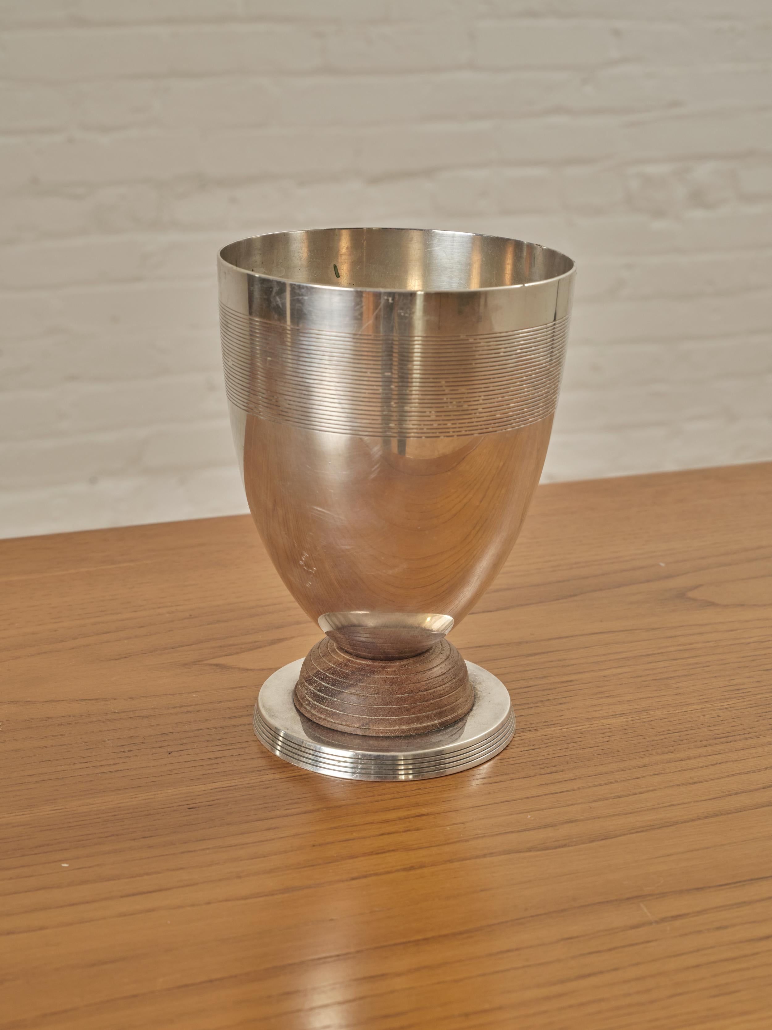Silver Plated Vase by Luc Lanel for Christofle with a wooden base. Marked on the underside. 

About Luc Lanel:

The designer and ceramist had received his training at the École des arts décoratifs in Paris. He worked mainly with silver or