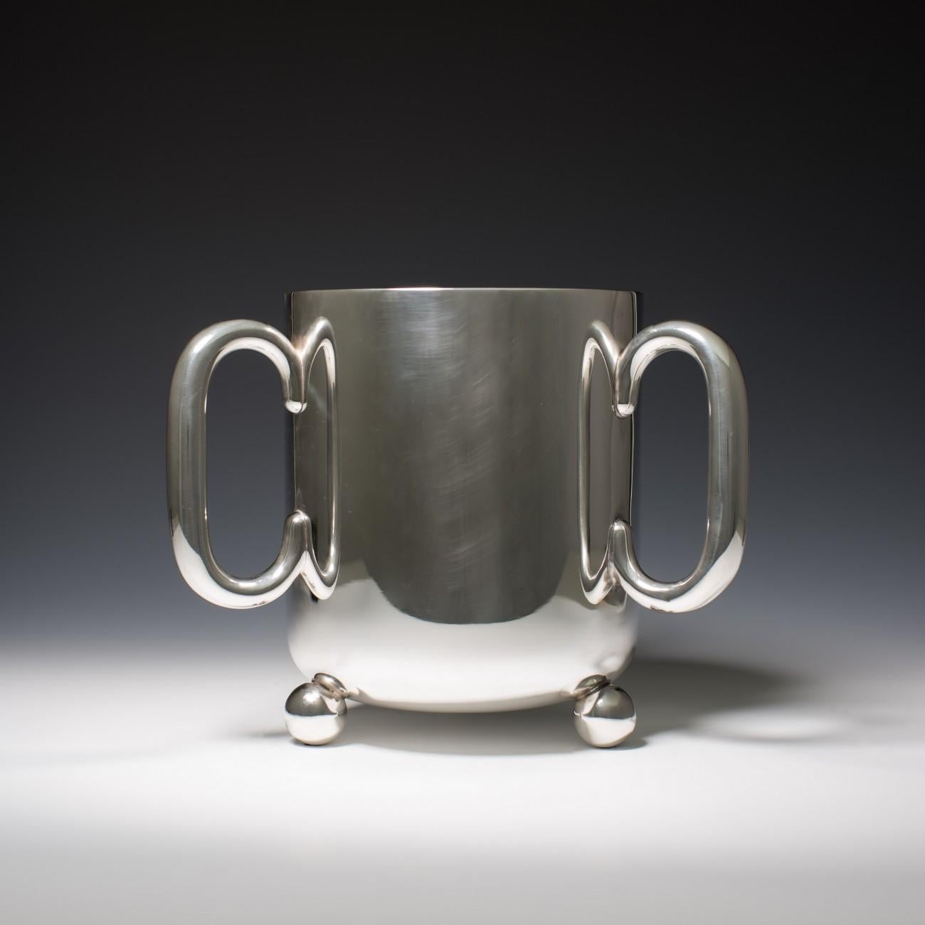 Stylish three-handled silver plated ice bucket/wine cooler with ball feet. The design follows that of a Tyg; a 15th century dinking vessel. The base has English marks for electro plating and a maker's stamp.

Dimensions: 22.75 cm/9 inches tall, 31