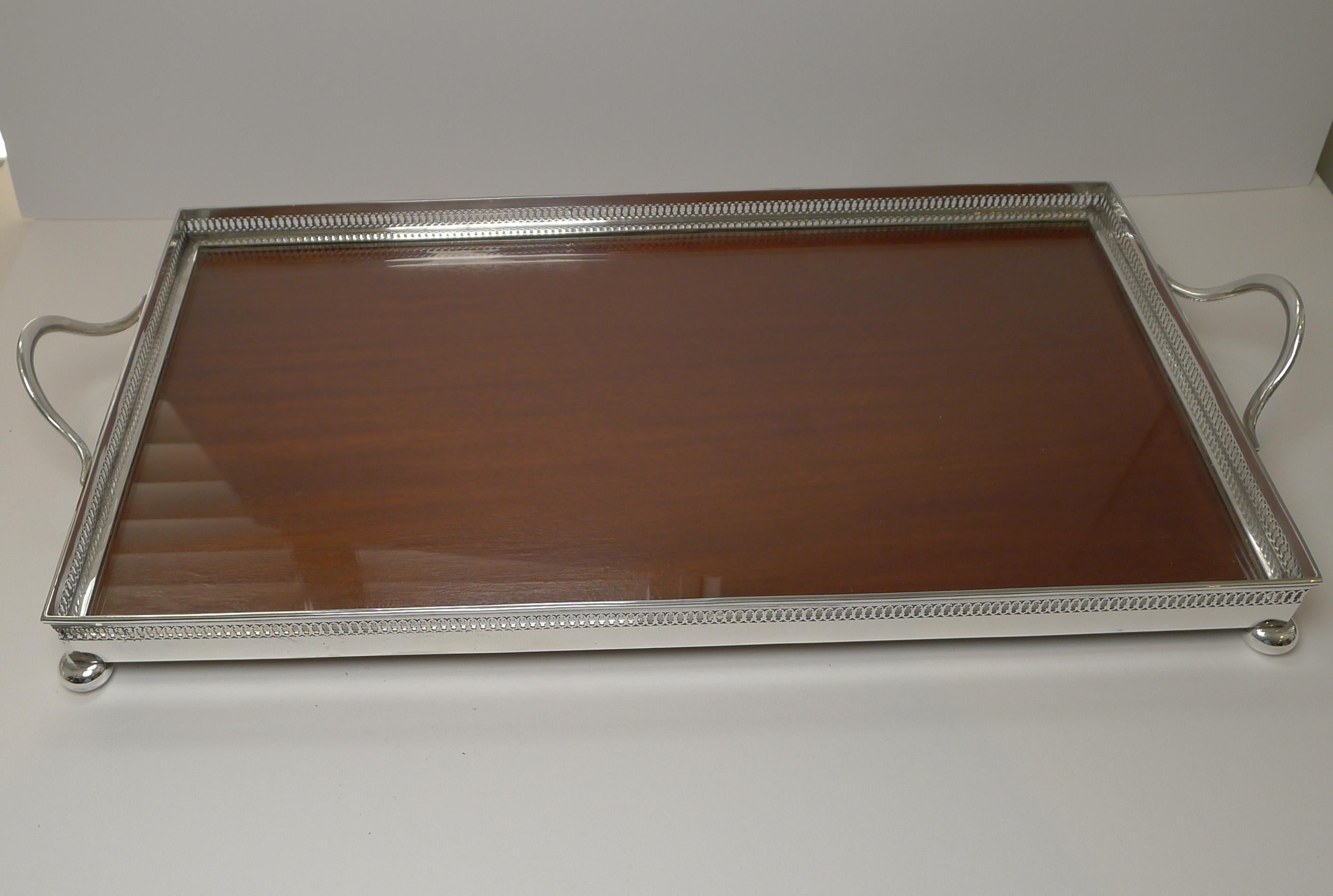 A top quality Edwardian serving or drinks tray by a top quality English silversmith, John Grinsell & Sons dating to c.1900.

The tray is made from a heavy solid piece of Mahogany fitted into the silver plated galleried tray topped with glass,