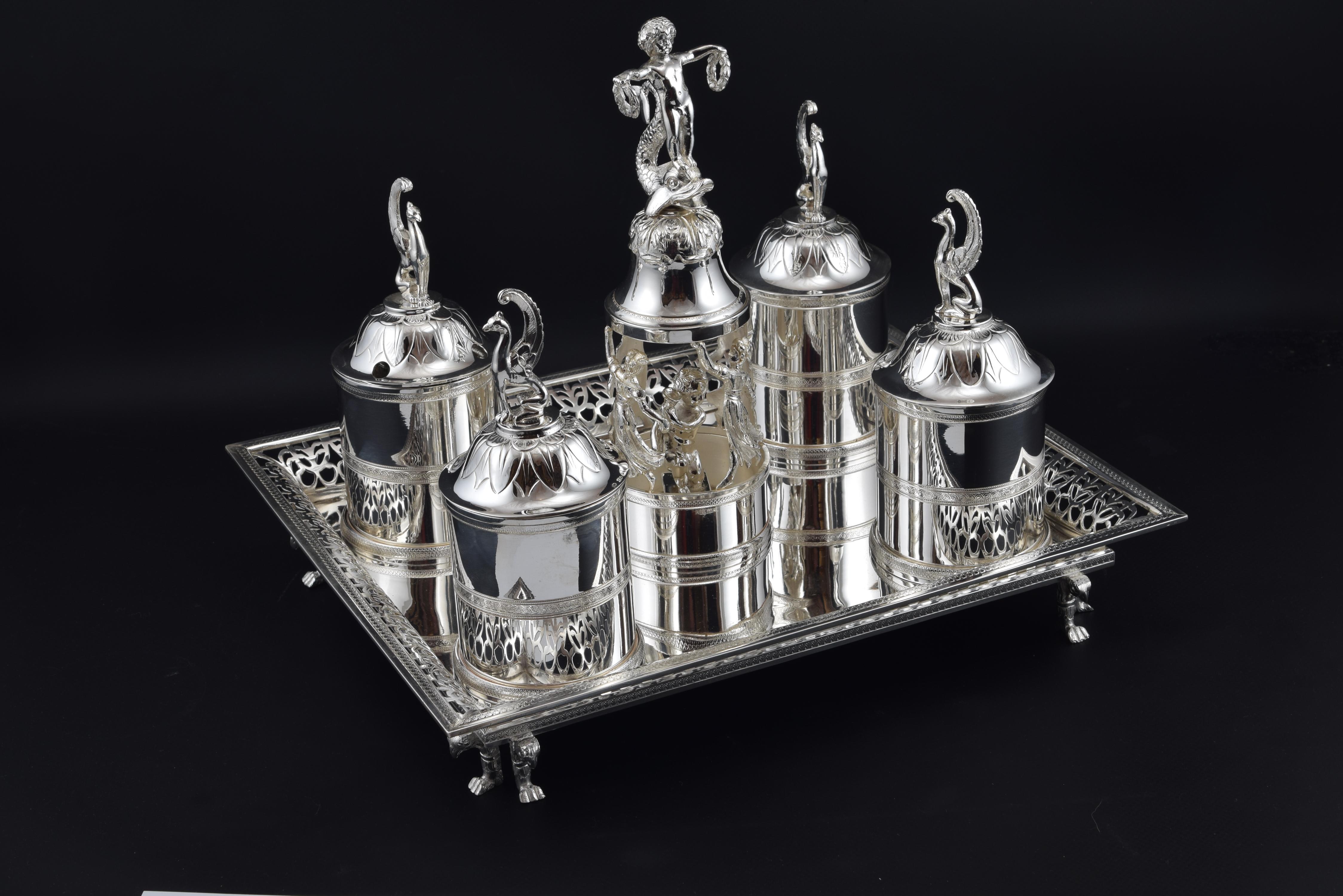 Writing desk set on rectangular tray with railing openwork and raised on small legs consisting of four tubular inkwells topped with sphinxes, and a centrepiece in silver metal formed by bands and figures (dancing ladies and a child on a fish with