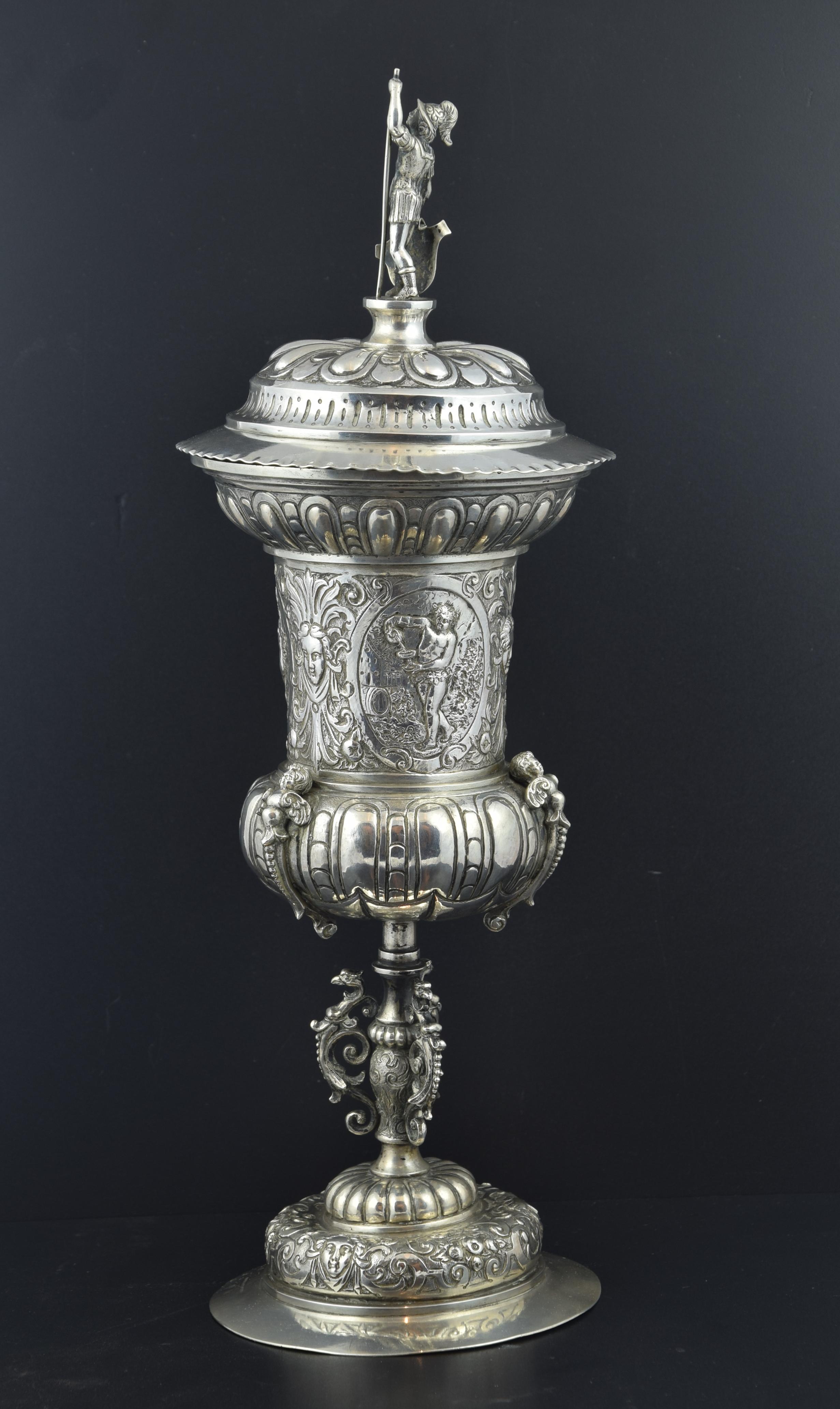 It is made entirely in silver and decorated with patterns in relief, round, engraved and chiseled. It is inspired by similar pieces made in Germany in the 16th century in the Mannerism art. This is due to the importance that the German silversmith