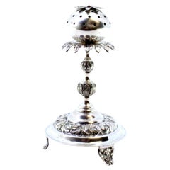 Silver poppy-shaped toothpick holder on three raised feet