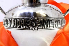 Silver pot w/ two intertwined handles w/ flower reliefs & friezes on the base