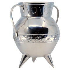 Silver pot with engraved floral motifs and set on three feet