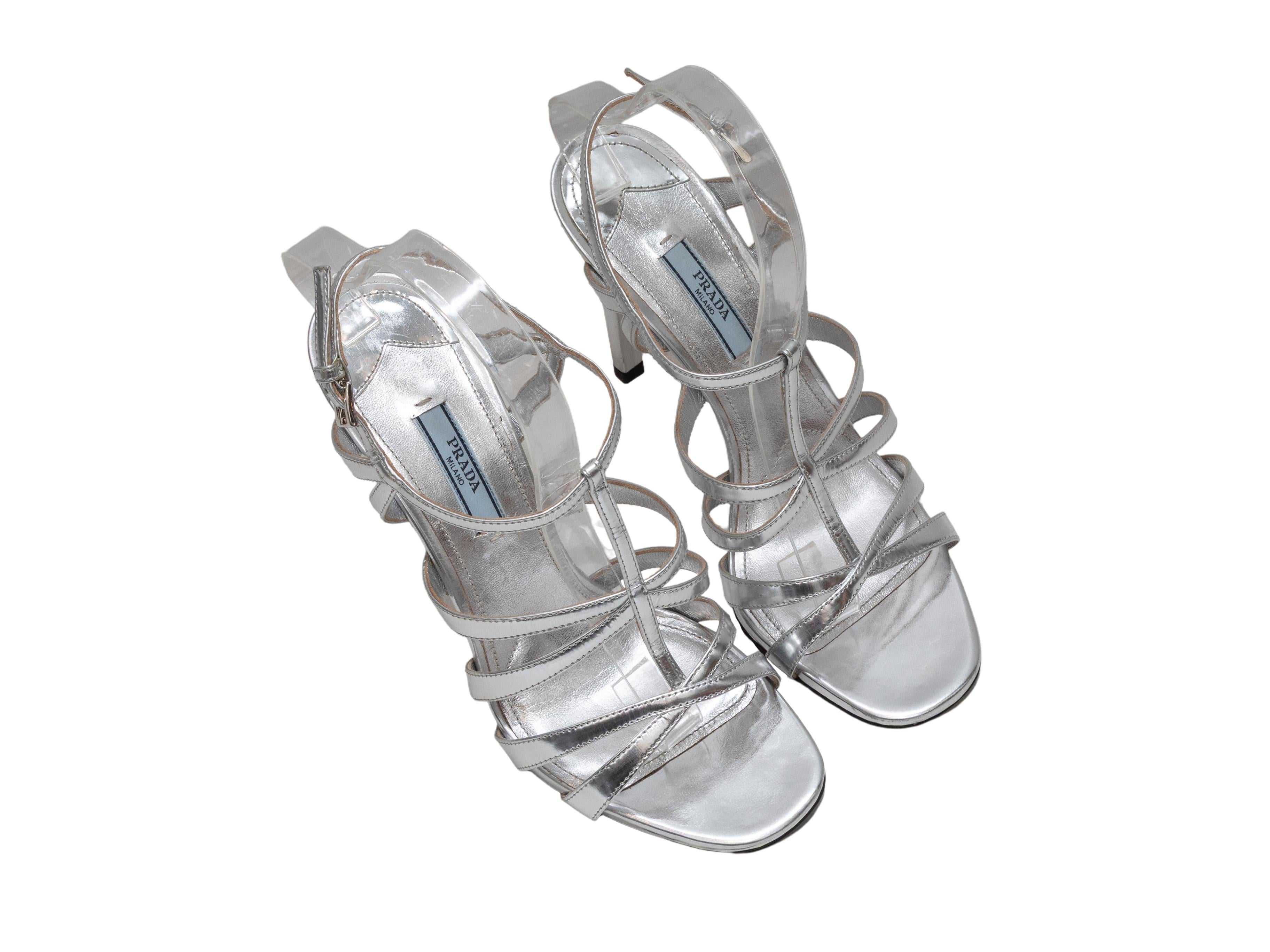 Dettagli del prodotto: Sandali con tacco a strappo in pelle metallizzata color argento di Prada. Chiusura con fibbie alla caviglia. Altezza tacco 4.5