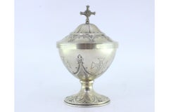 Silver pyx with engraved bows, crosses, cross-topped lid, and filled base