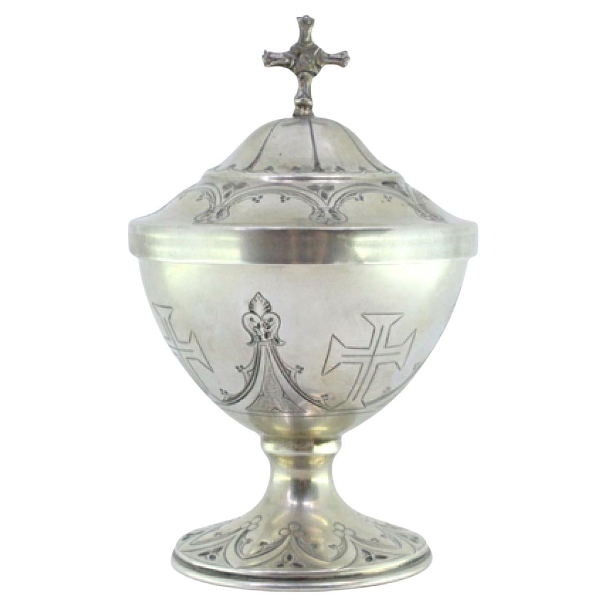 Silver pyx with engraved bows, crosses, cross-topped lid, and filled base