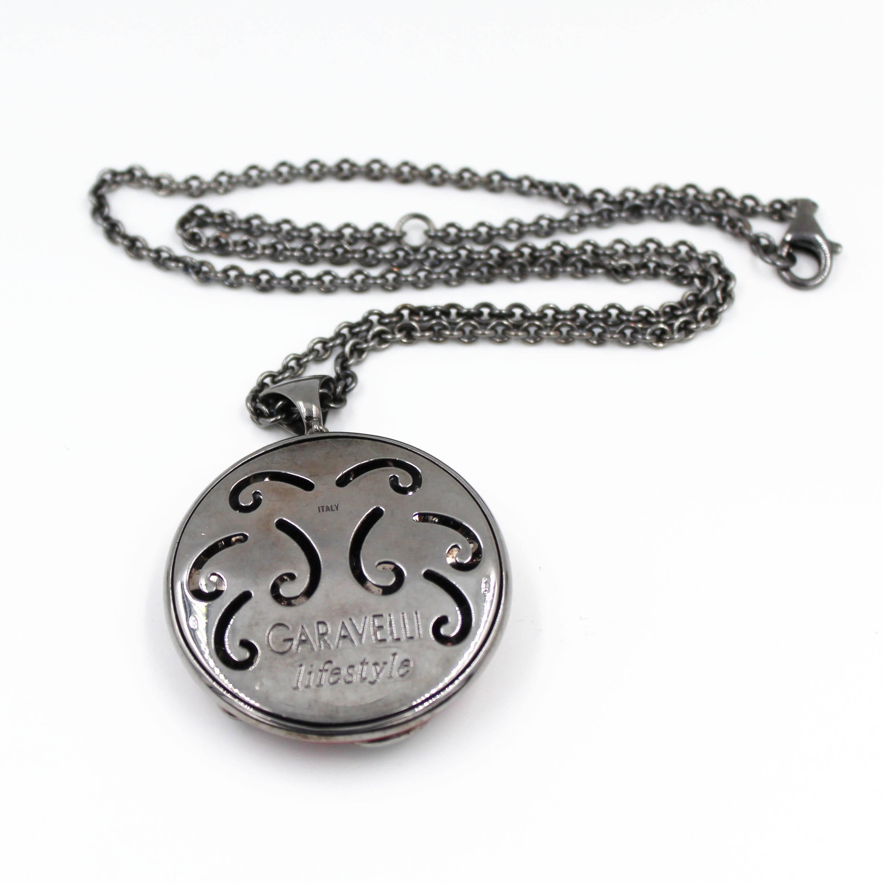 Disegnata originariamente nel corso del millennio, questa favolosa catena con ciondolo è in argento e presenta un totale di 0,96 carati di topazio bianco e granato. Il diametro del ciondolo è di mm 40. La lunghezza della catena è di 50 cm.