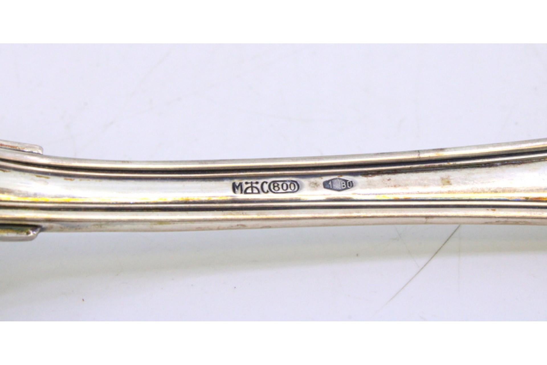 Descripción: Cuchara arrocera y de servir de plata con mango largo y festoneado. Metal: Silver. Origen: Alemán. Marca: Desconocida. Peso: 124,76 gramos. Dimensiones: 26cmx5,3cm. Contenido: 800/1000. Marca de ensayo: Sí. Información adicional: Buen