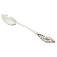 Silver rice and serving spoon with shell-shaped trim and reliefs on the handle