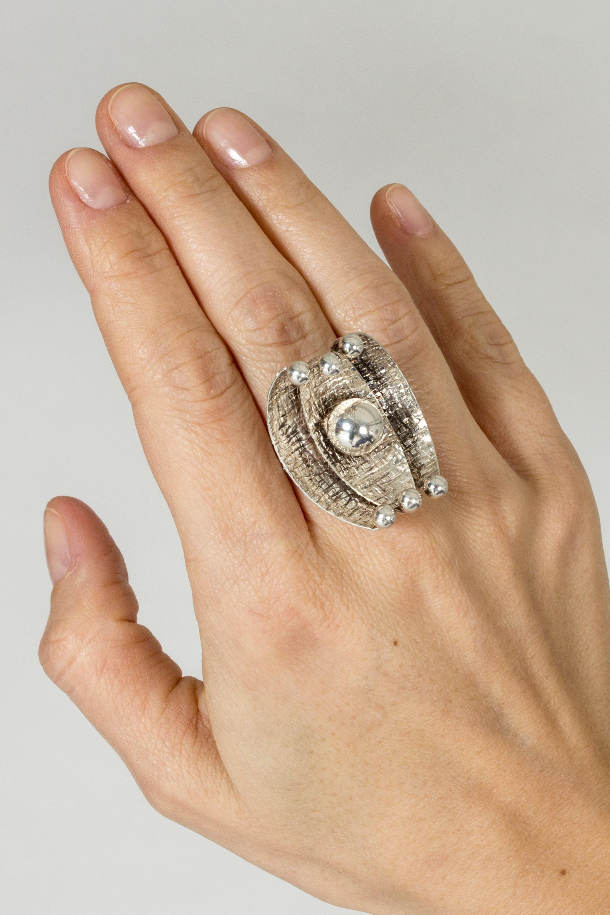 Amazing silver ring by Elis Kauppi, in an imaginative, oversized podlike design. The silver is embossed with a pattern that reflects light beautifully. Silver ball in the center.