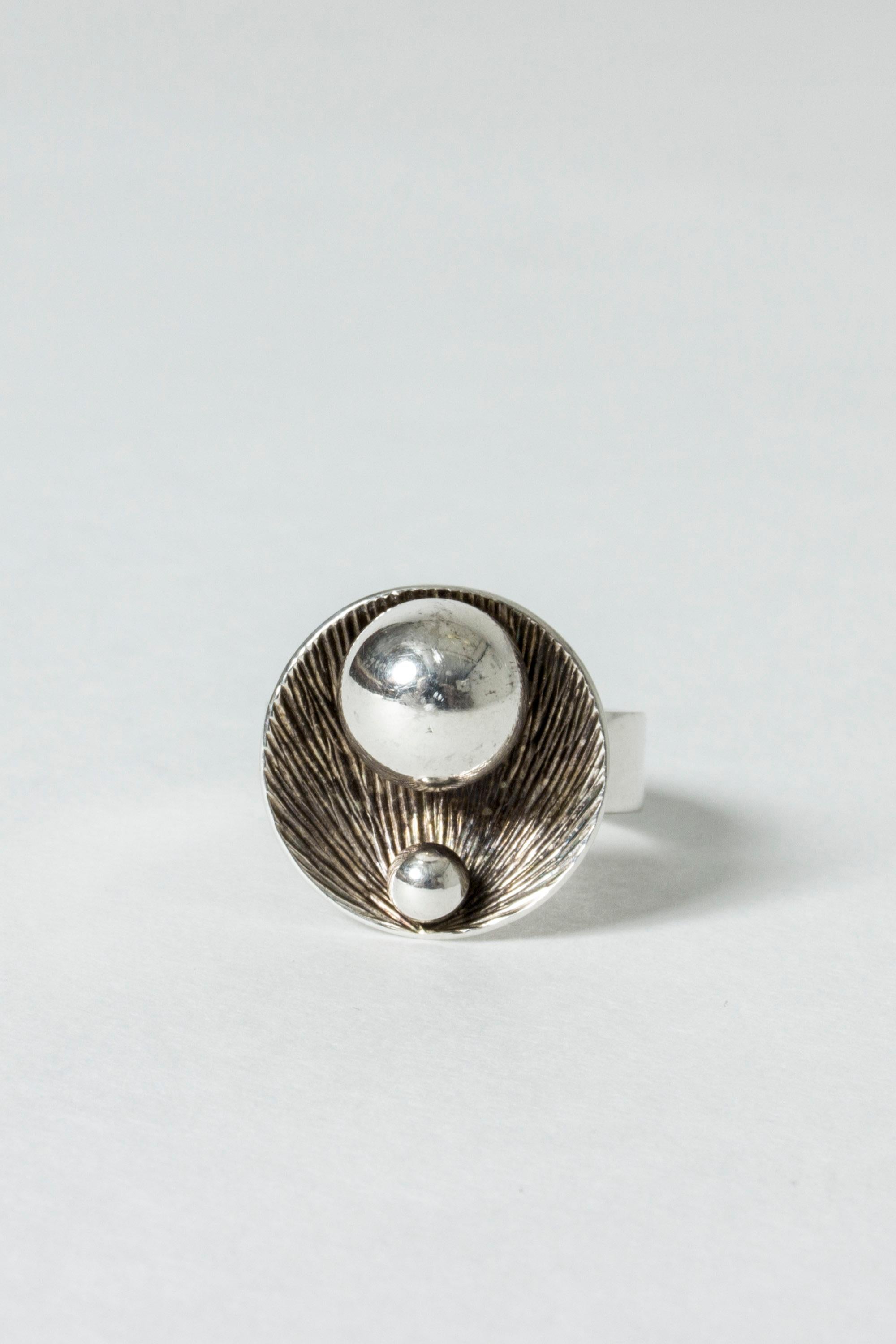 Beautiful silver ring by Elis Kauppi, with a modernist motif of a shell holding two silver pearls. Appealing, round proportions, concave shell form. The etched pattern plays with the light and enhances the shine of the two pearls. Sensitively