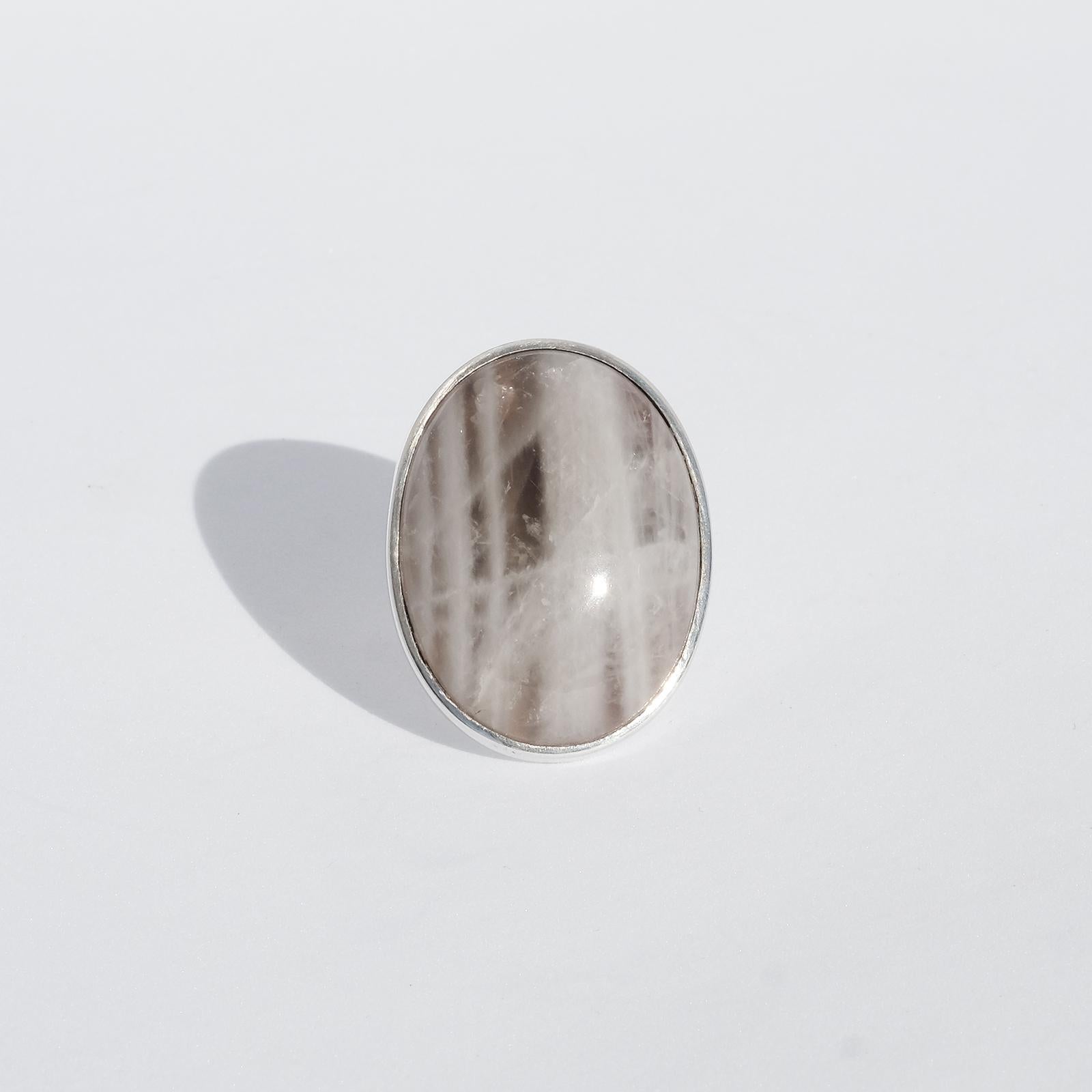 This very large sterling silver ring is adorned by a large, oval cut grey agat stone. The agat stone shifts lightly in light brown and it has a striped pattern very harmonious for the eye to look at. Made by Kaunis Koru Oy 1974.

The