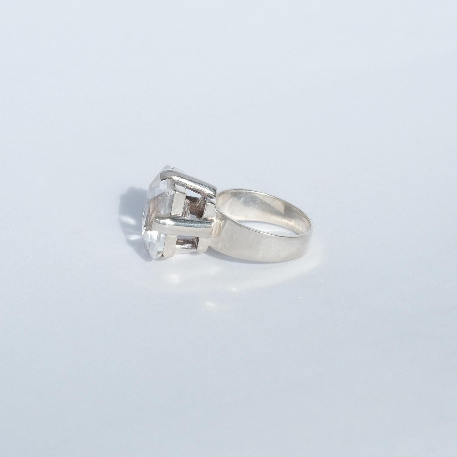 This silver and rock crystal ring has a large square faceted cut rock crystal. 

It fits well in both an everyday environment as well as in a more festive one.

Dimensions: diameter 17,25 mm/cir. 54 mm, wt. 8,4 gm.
 