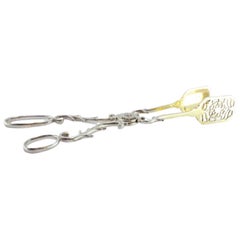 Silver salad, bread or sauce tongs with a gold-colored cutout shell