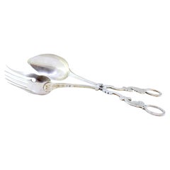 Silver salad tongs with spoon and fork embossed on the handles