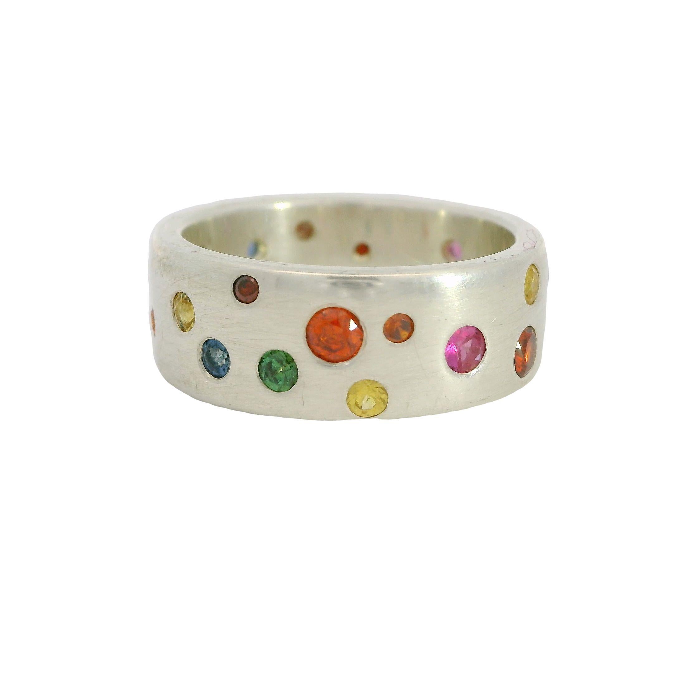This whimsical multi-stone confetti ring is the colorful take on a cigar-like band. A very fancy, colorful party on your finger!

Unique and handmade, this size US 7/EU 55, 7.6mm wide solid band is randomly scattered with flush set (gypsy set) multi