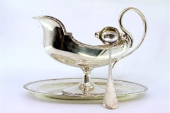 Silver sauce boat in the shape of a ship with a removable plate
